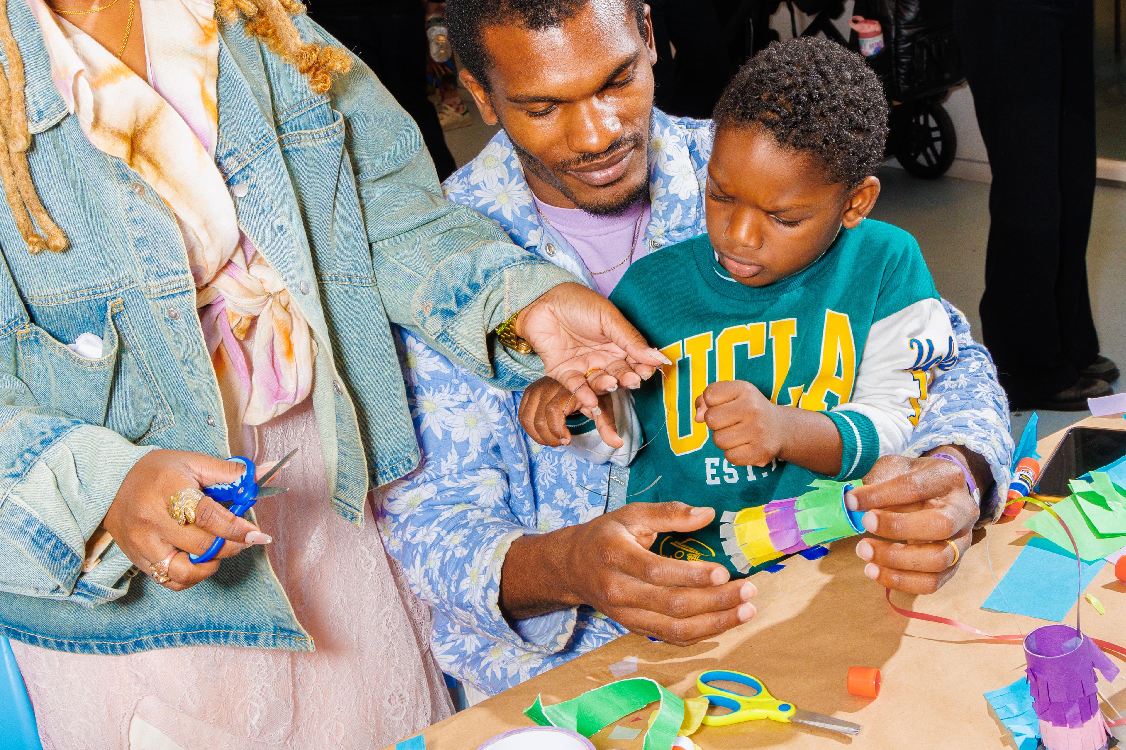 A child seated on an adult’s lap, doing an art project