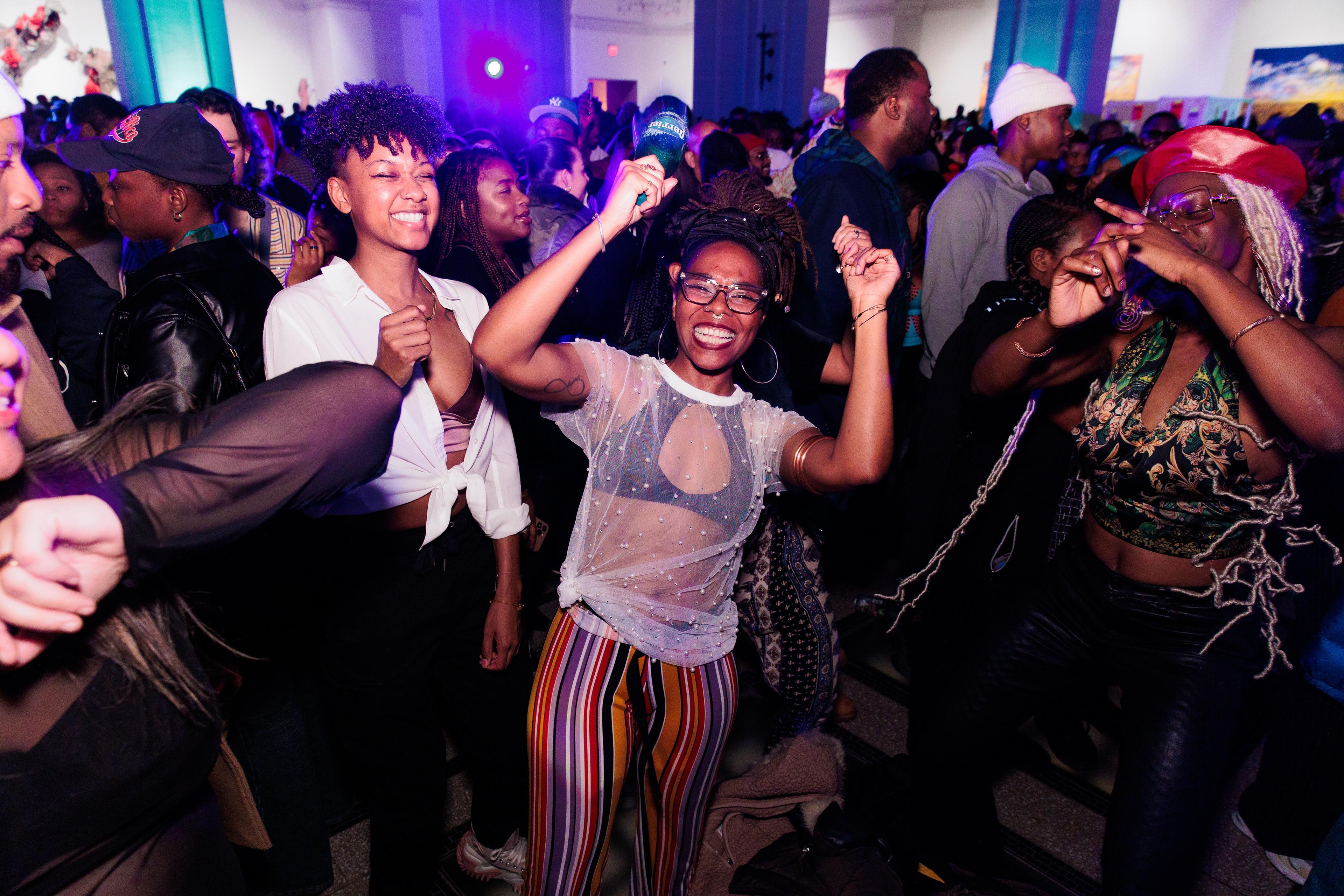 Group of friends dancing and smiling in a dark crowded room