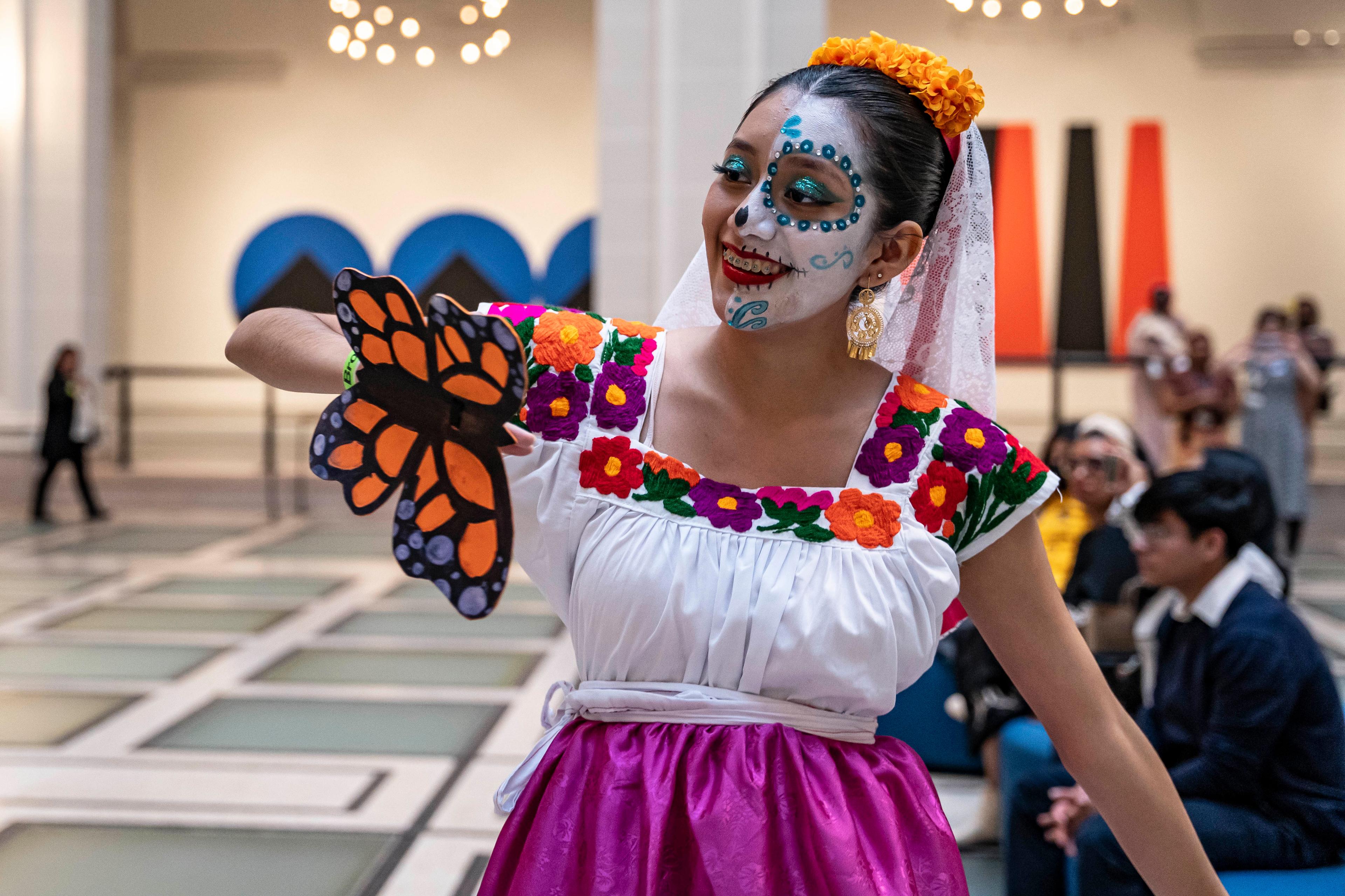 Person wearing Día de los Muertos makeup and a paper butterfly