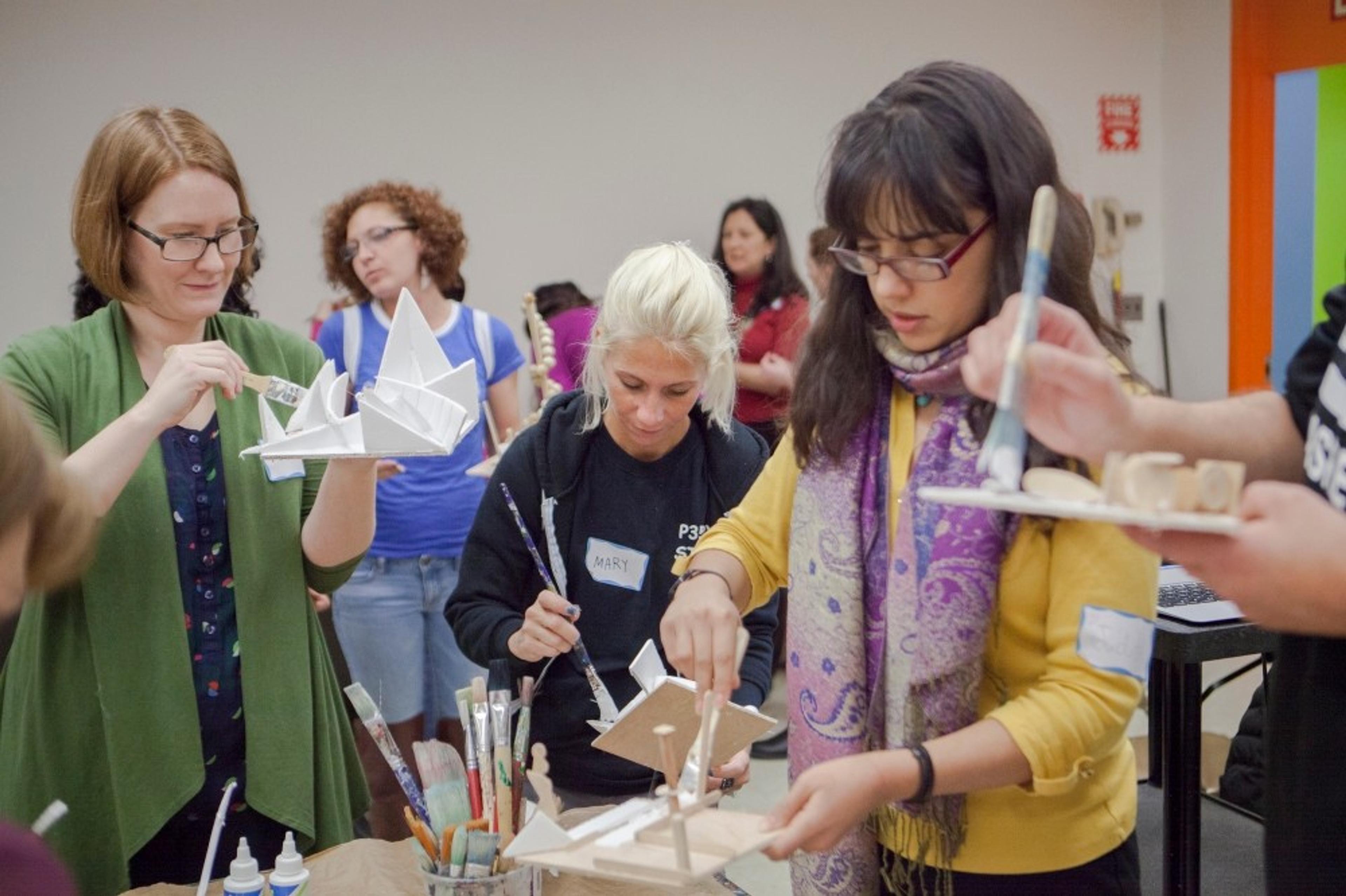 A group of adults hold and paint 3-D sculptures