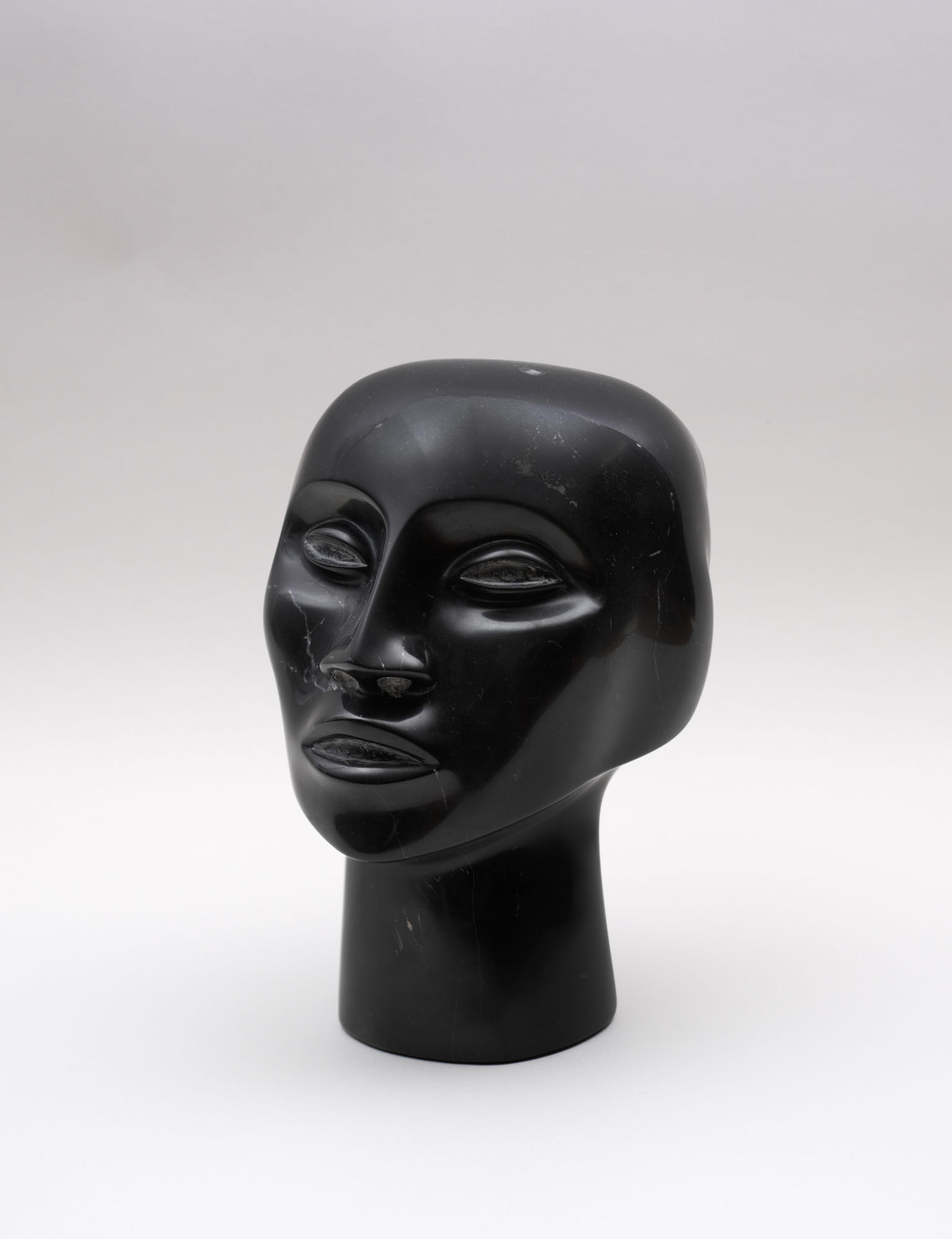 An all black sculpture of a person's head, set against a white backdrop