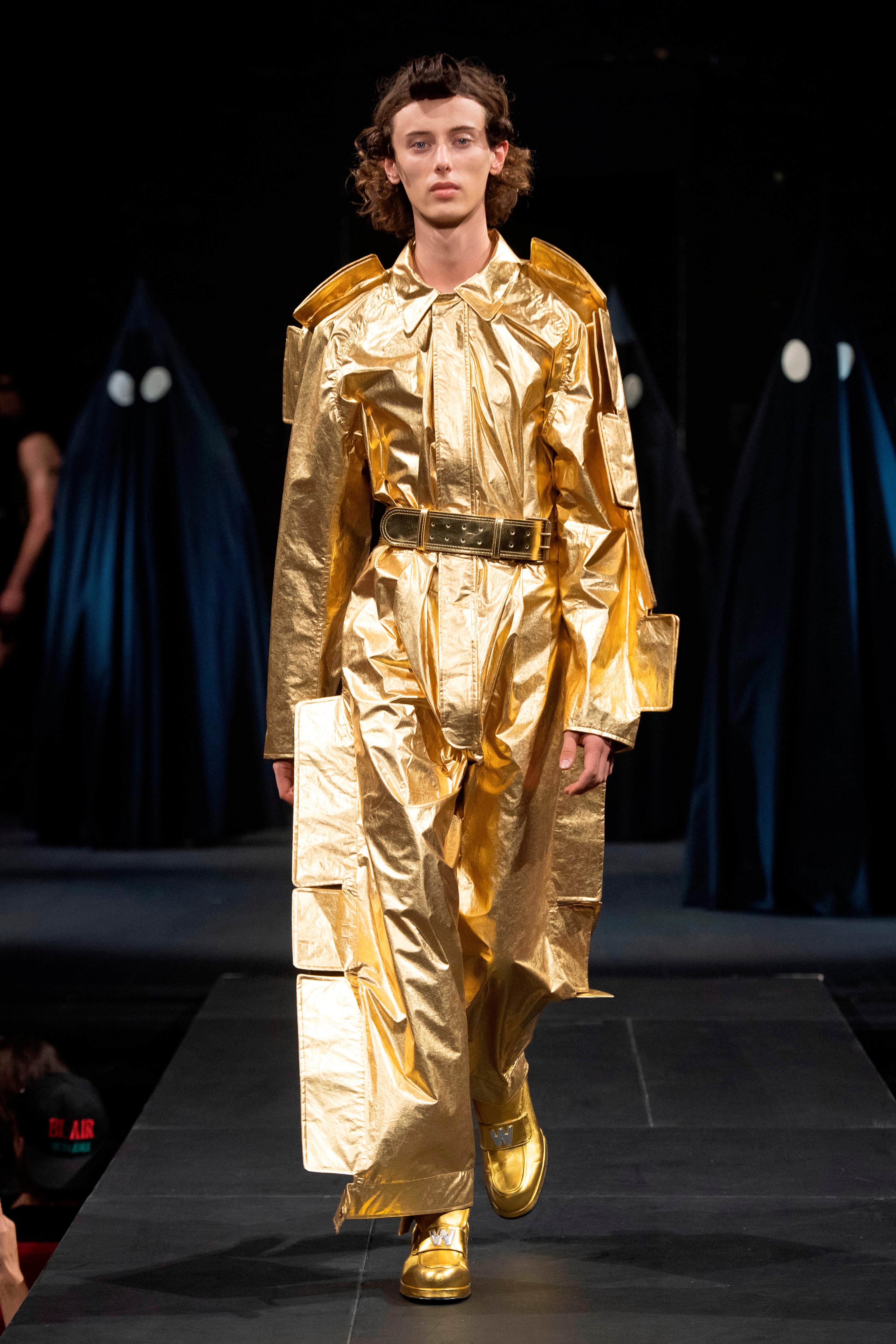 A model walking a runway in a gold ensemble