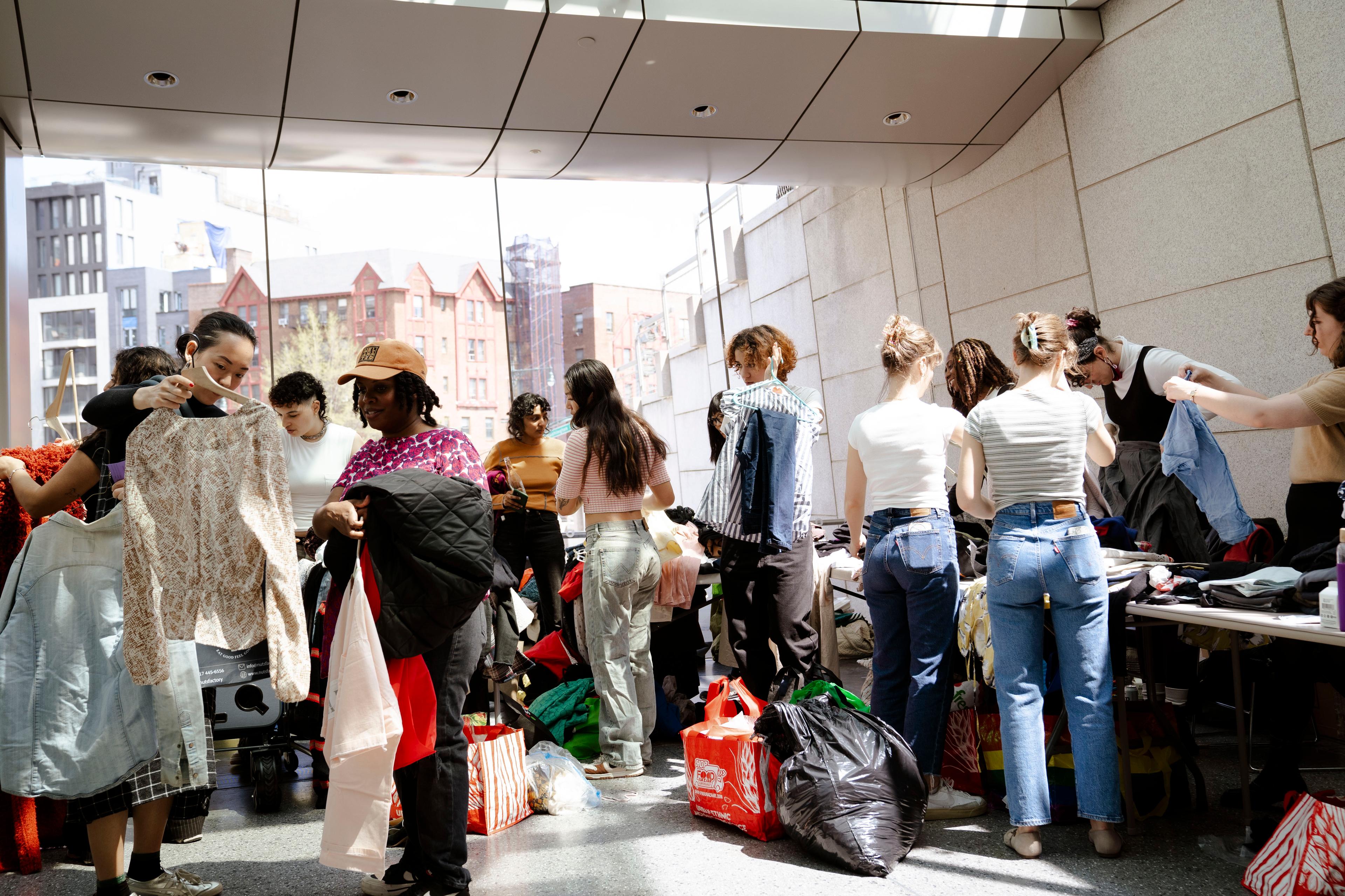 Crowd of adults look through clothing laid out on tables