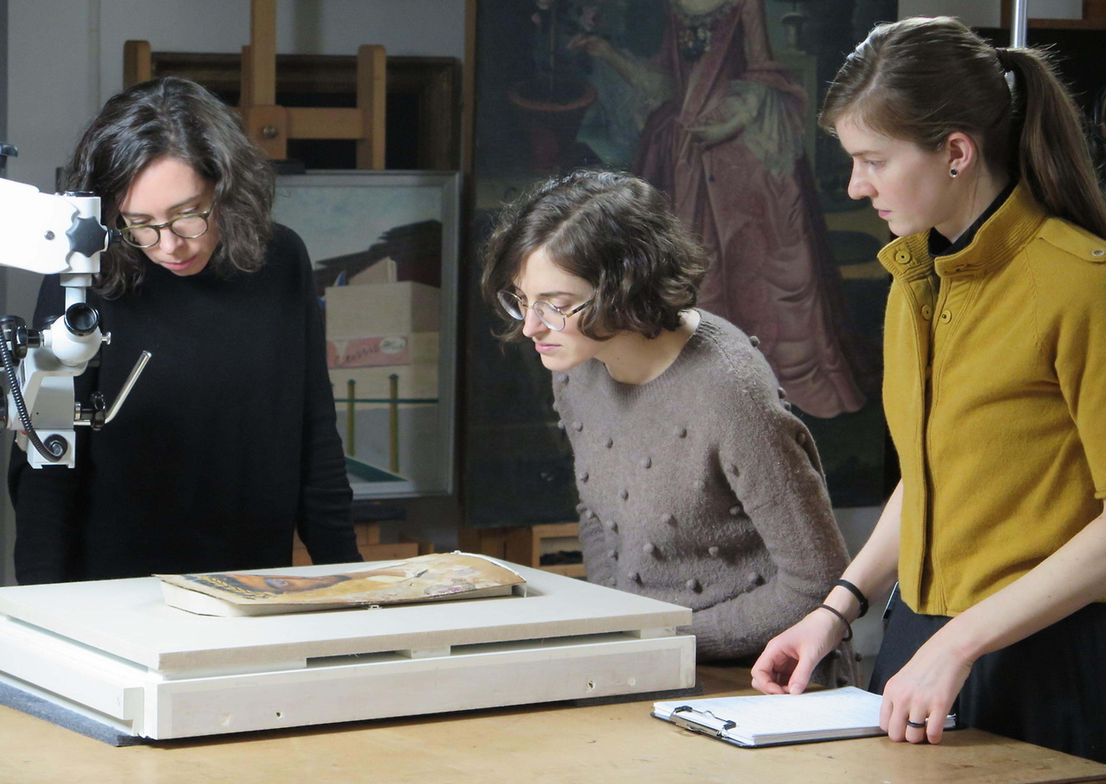 Three people examine an object in the Brooklyn Museum's Conservation department