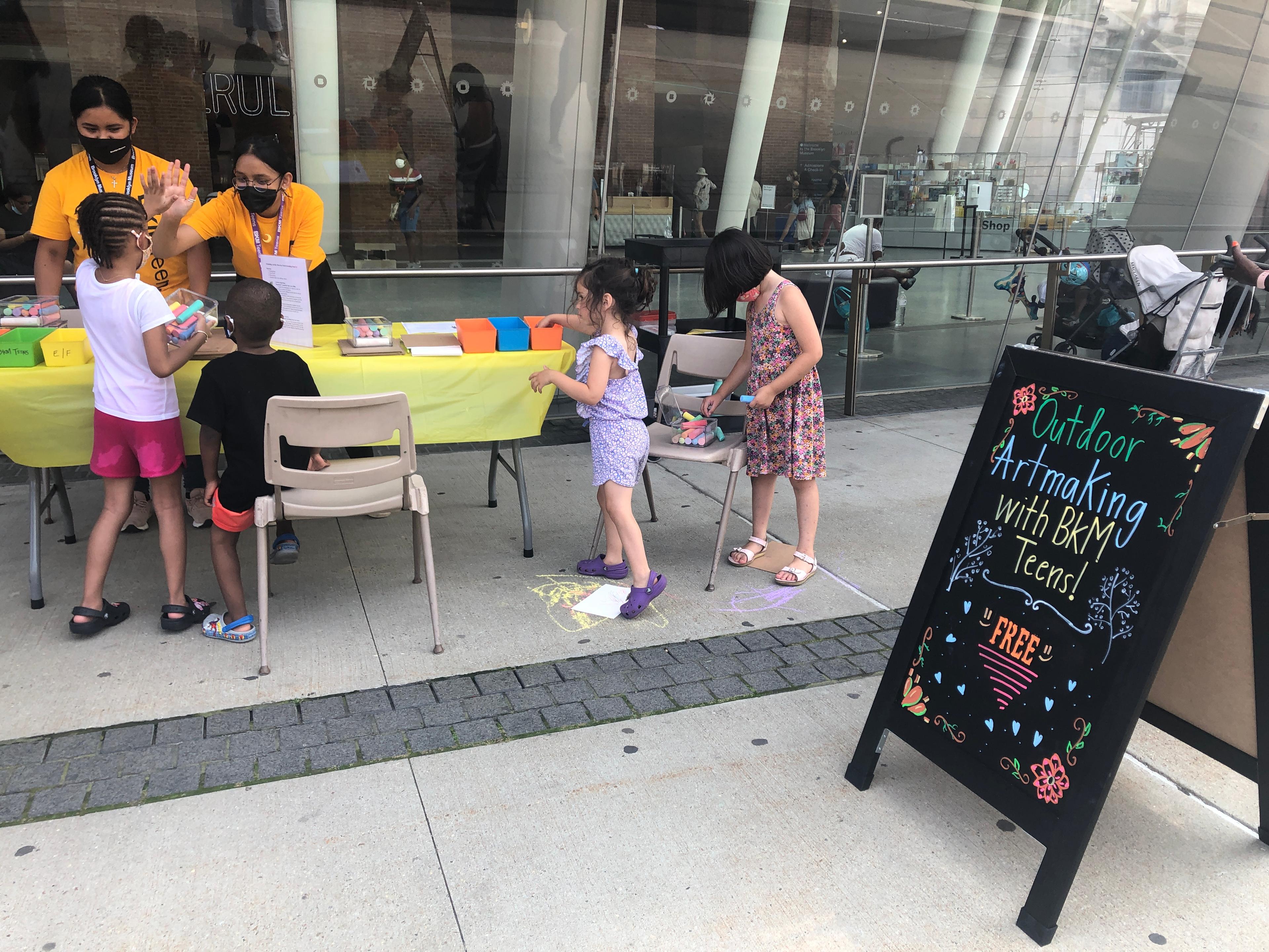 Teen staff helping young children with an art project
