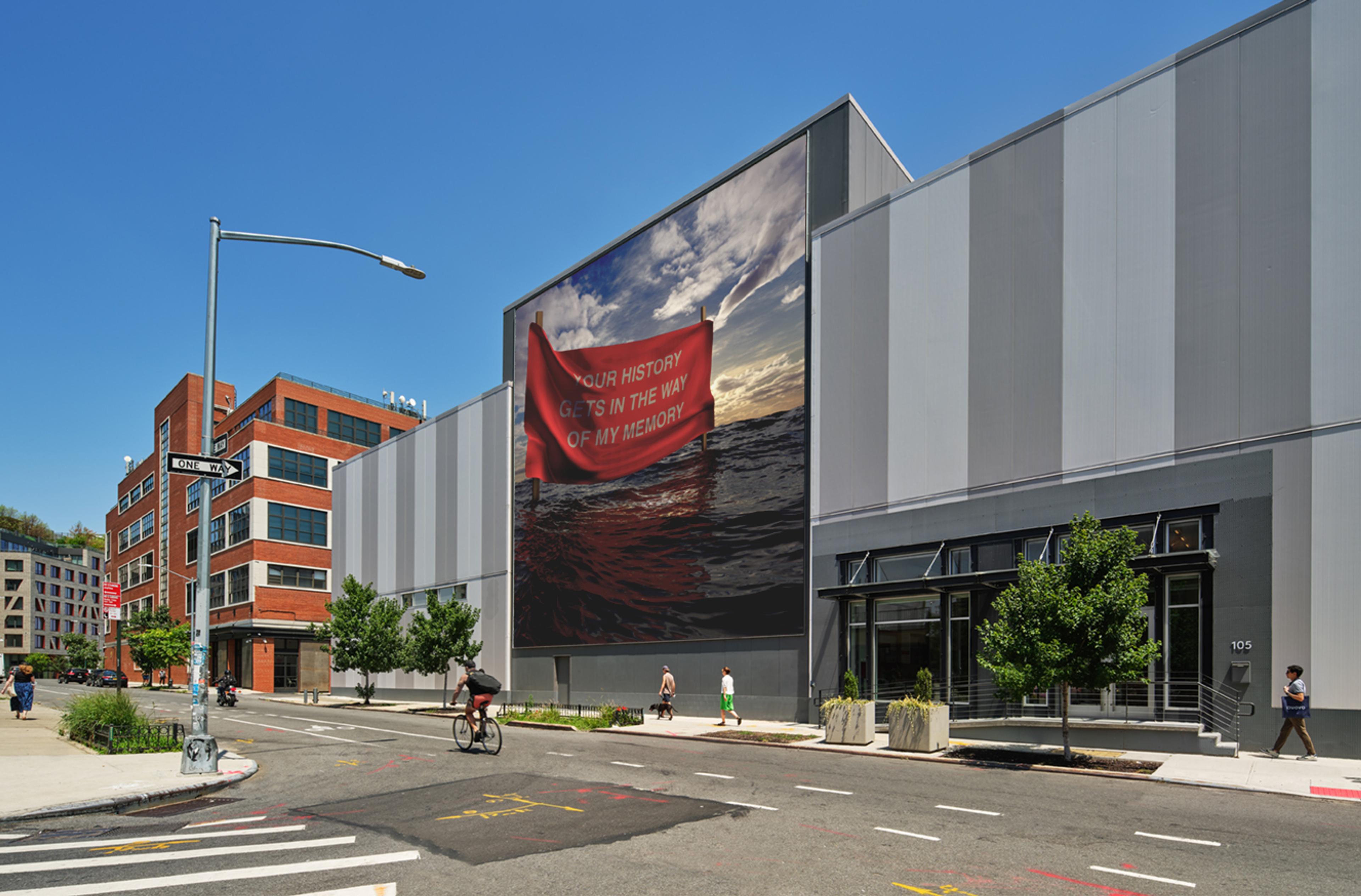 A warehouse building on a city street with a large photo mural in the center