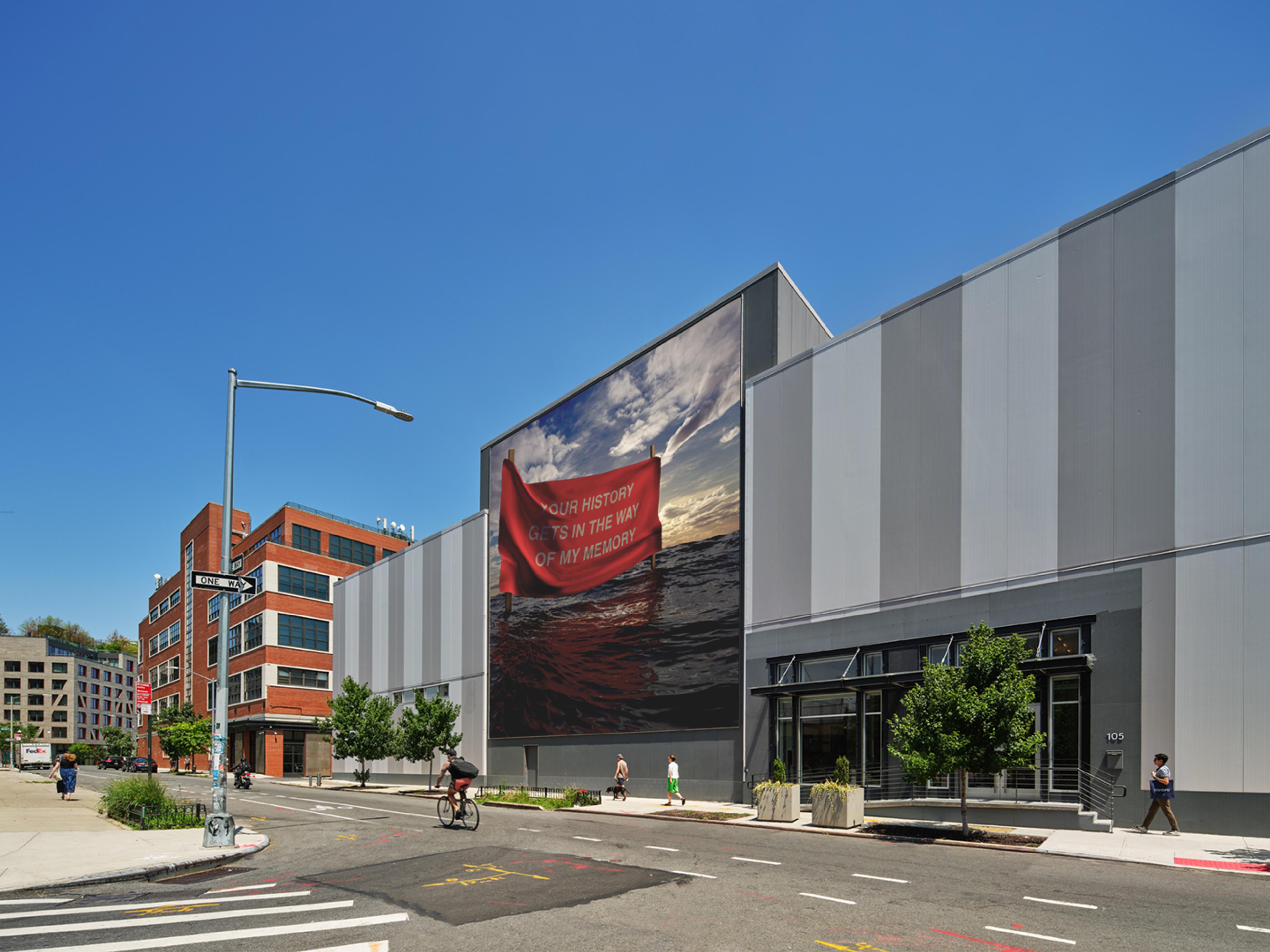 A warehouse building on a city street with a large photo mural in the center