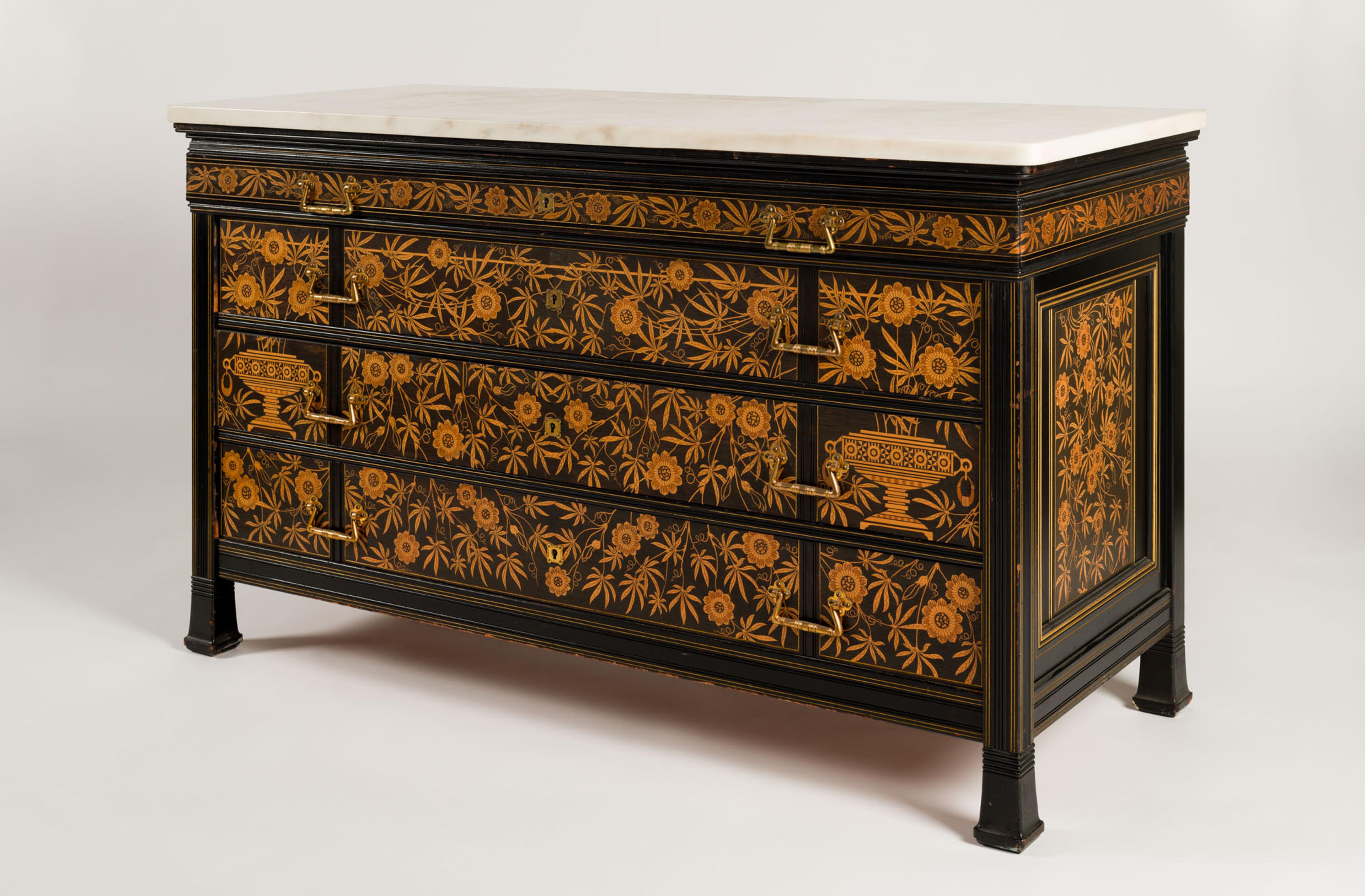 Photo of a chest of drawers with orange floral decorations on the drawers and side, and a white marble top