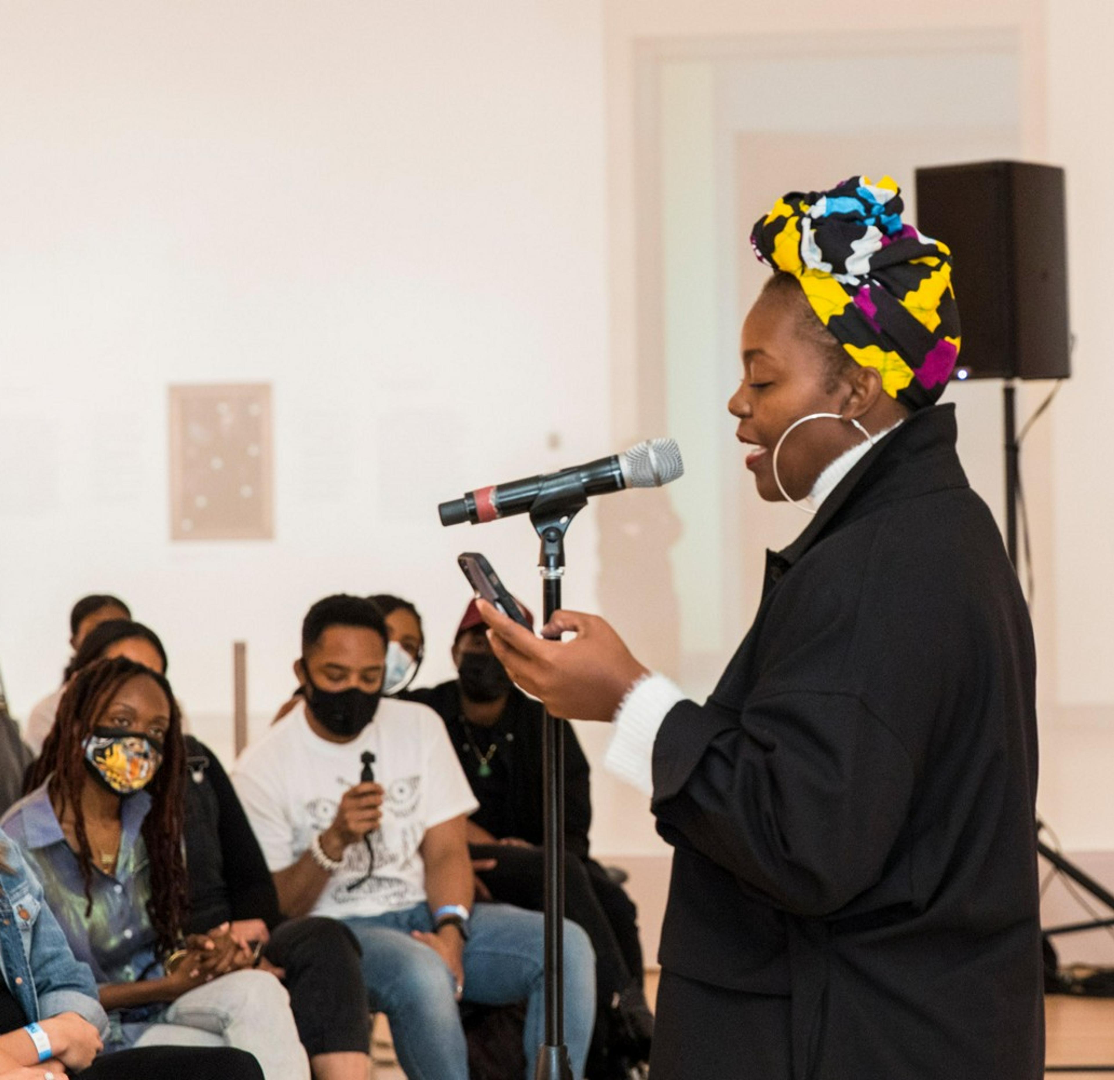 A person reading at a microphone in front of an audience