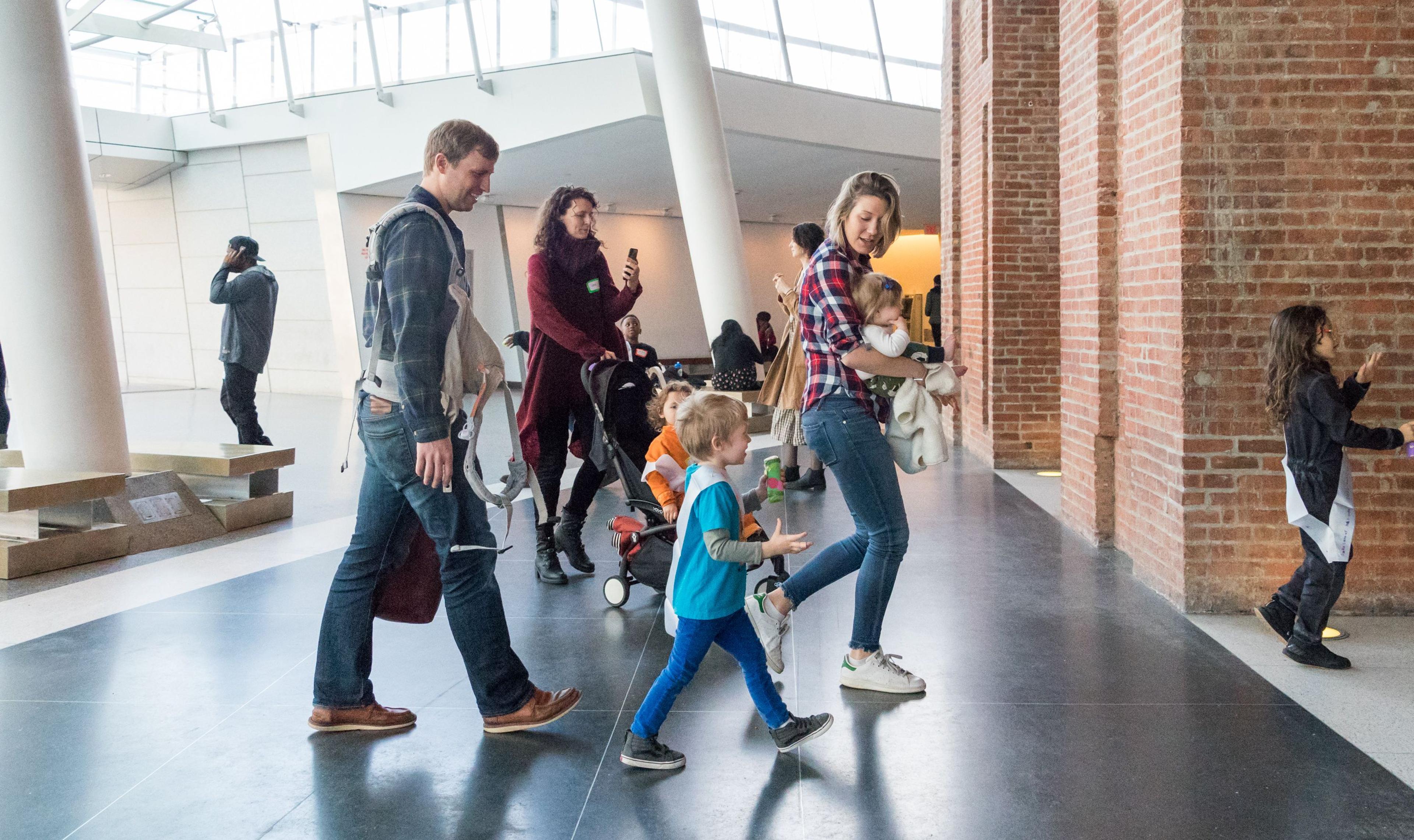 Two families with children walk through the museum lobby