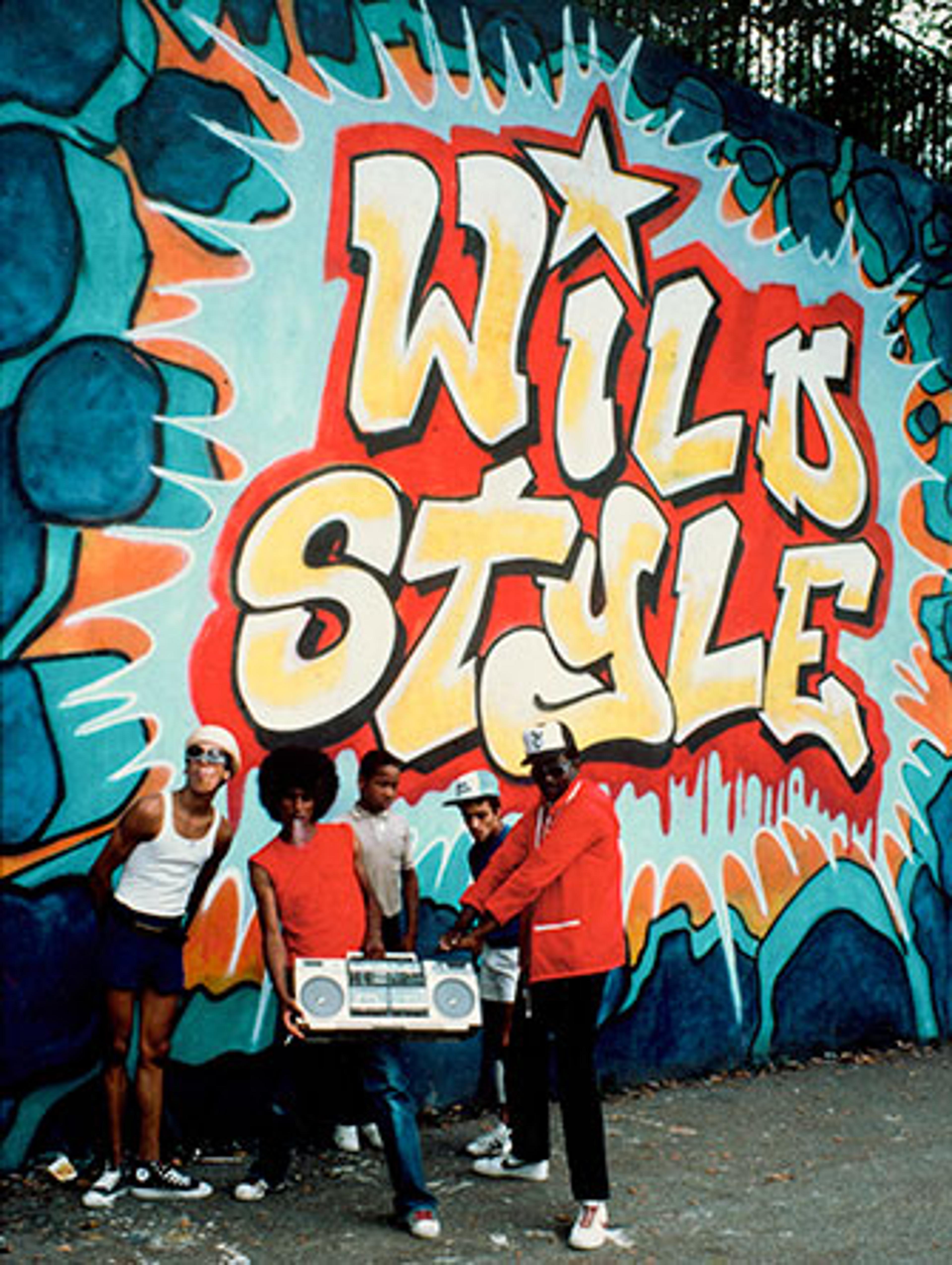 Fab 5 Freddy and Rock Steady Members in front of Wild Style mural by Zypher, Revolt, and Sharp, 1983. Photo by Martha Cooper