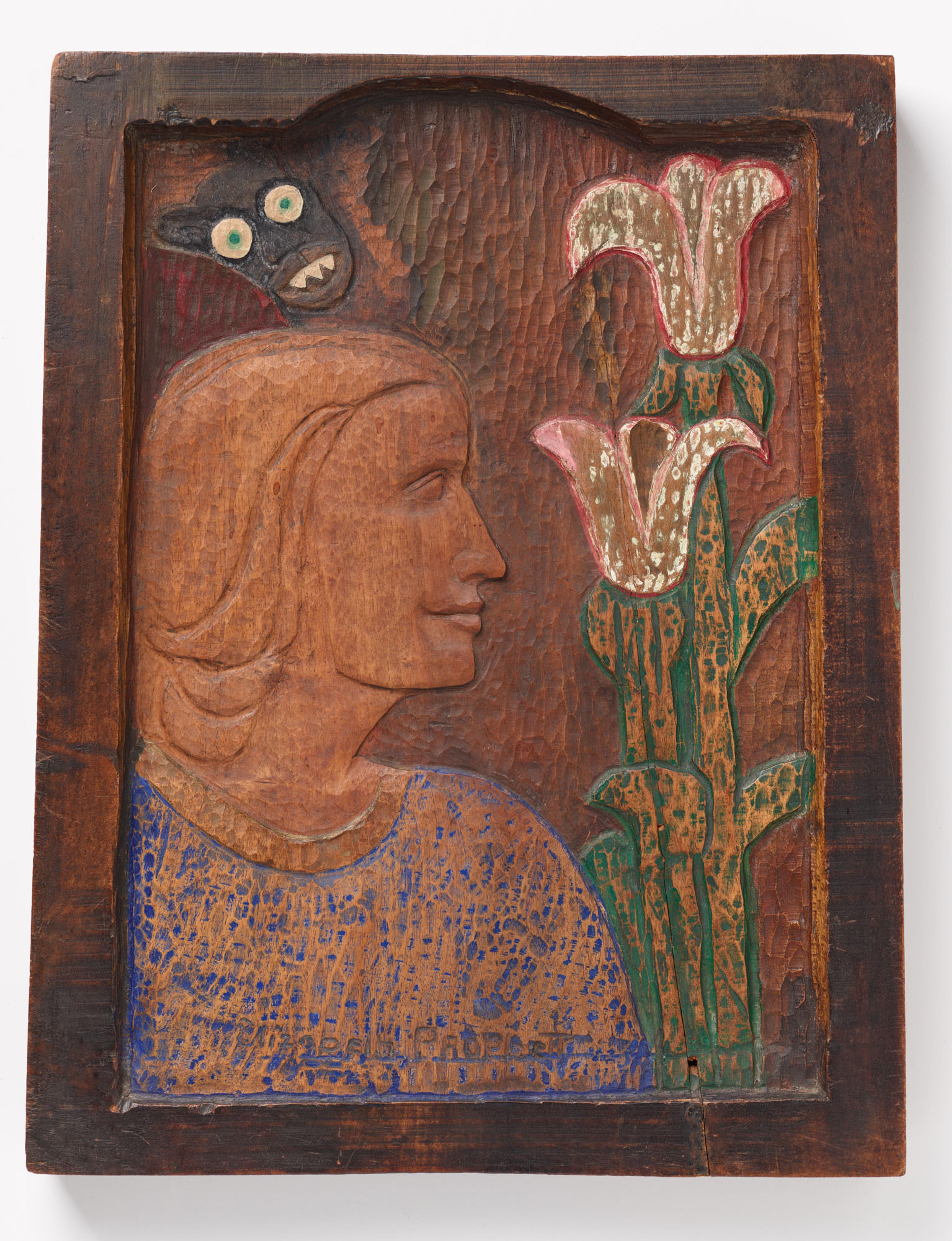 Wooden sculpture of a person in profile, flowers, and wide-eyed creature