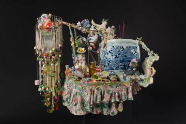 Colorful assemblage featuring ceramics, beads, figurines, and floral fabric
