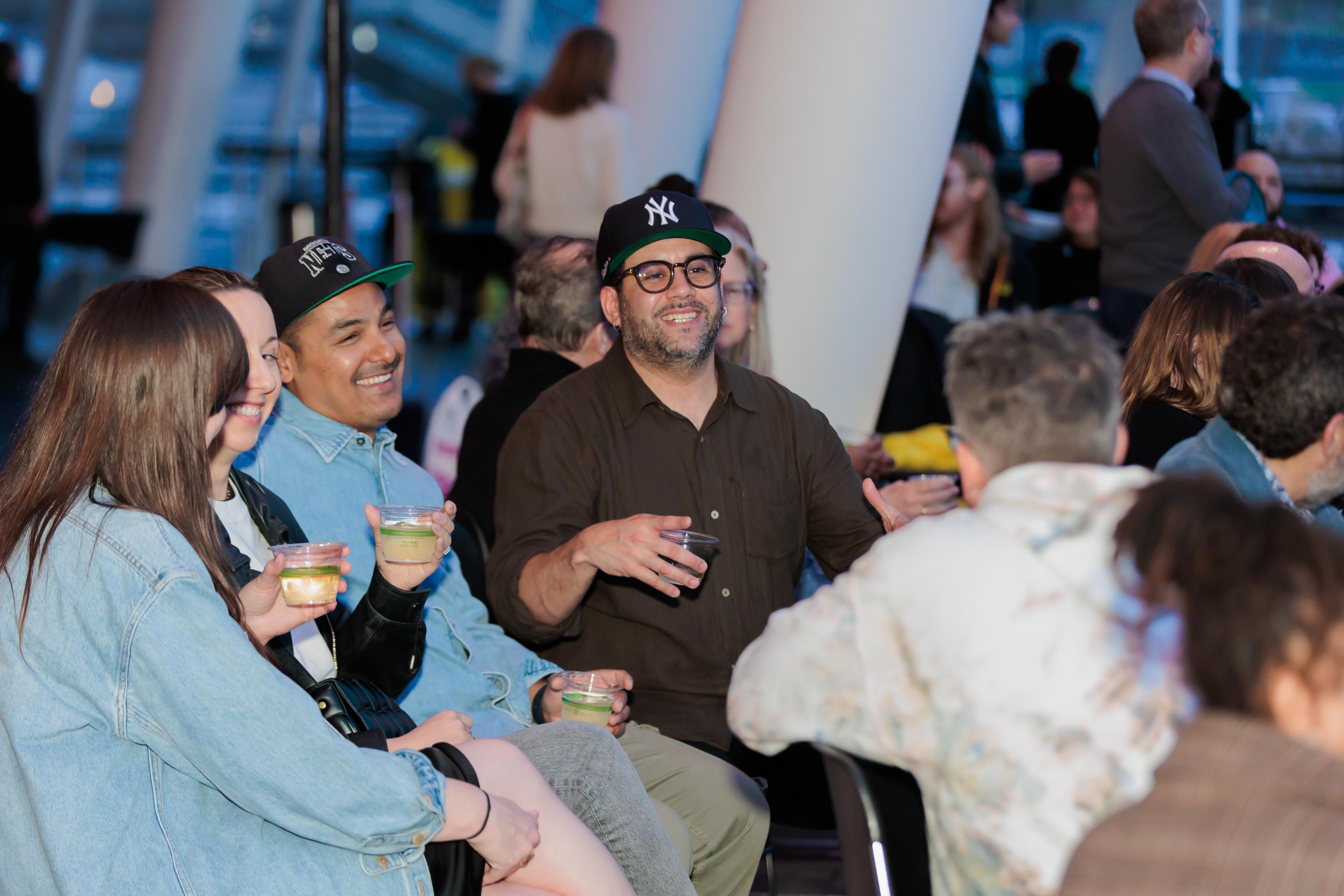 A group of people sitting together holding cups and smiling