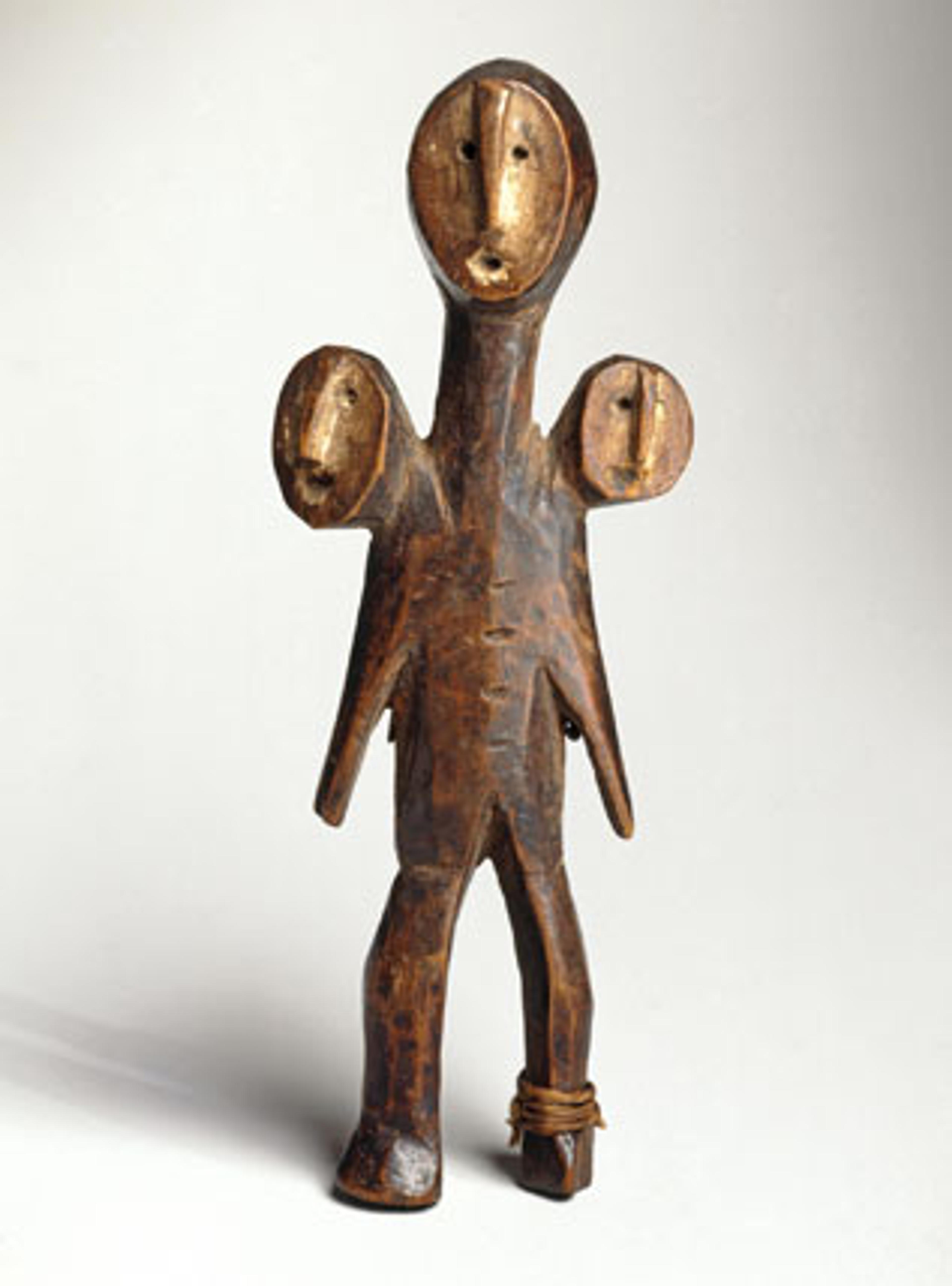 A carved wooden figure with three heads and a minimalist design