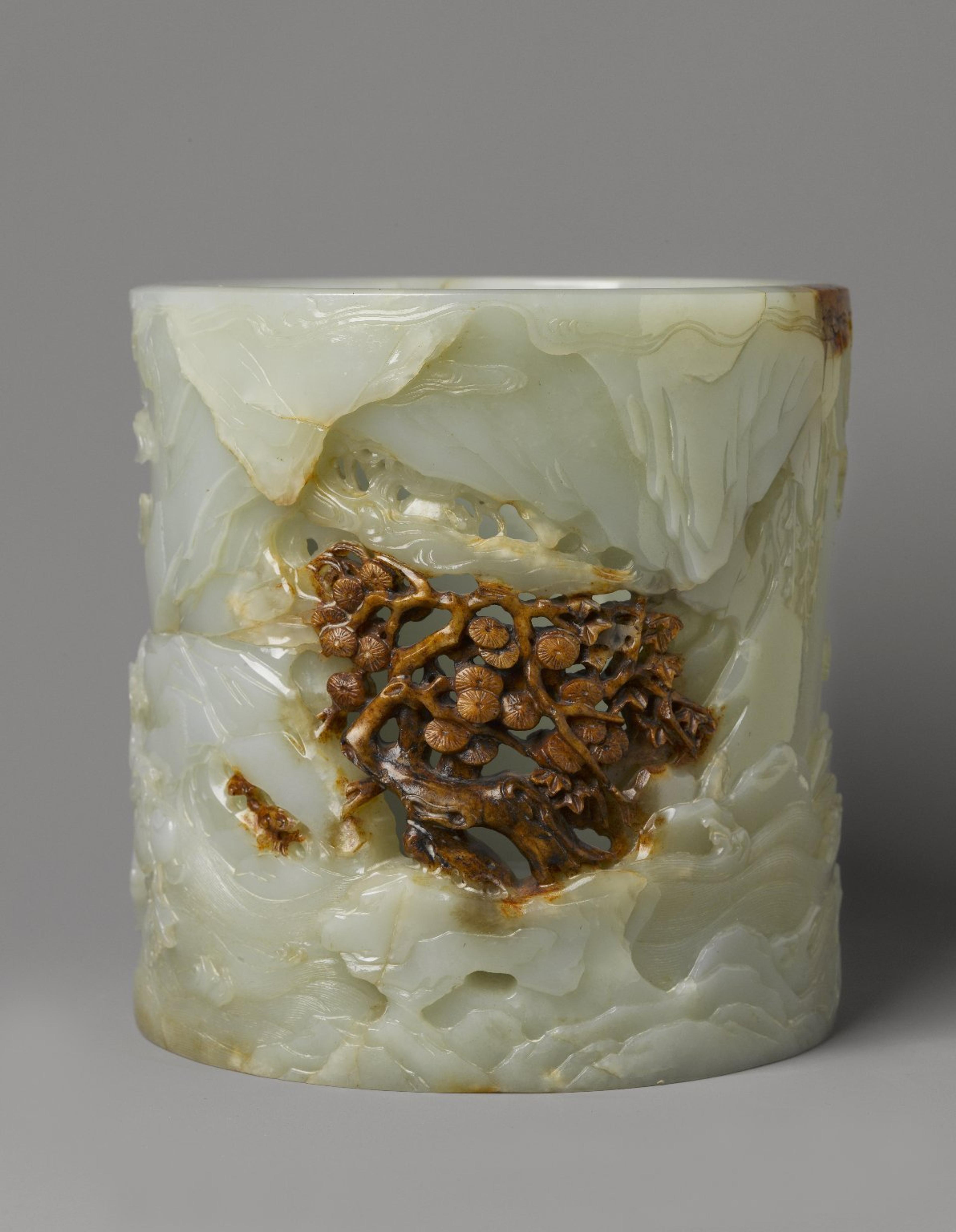 Cylindrical jar carved from light green jade, heavily decorated with images of nature, a brown imperfection in the stone is used in decorative scheme.