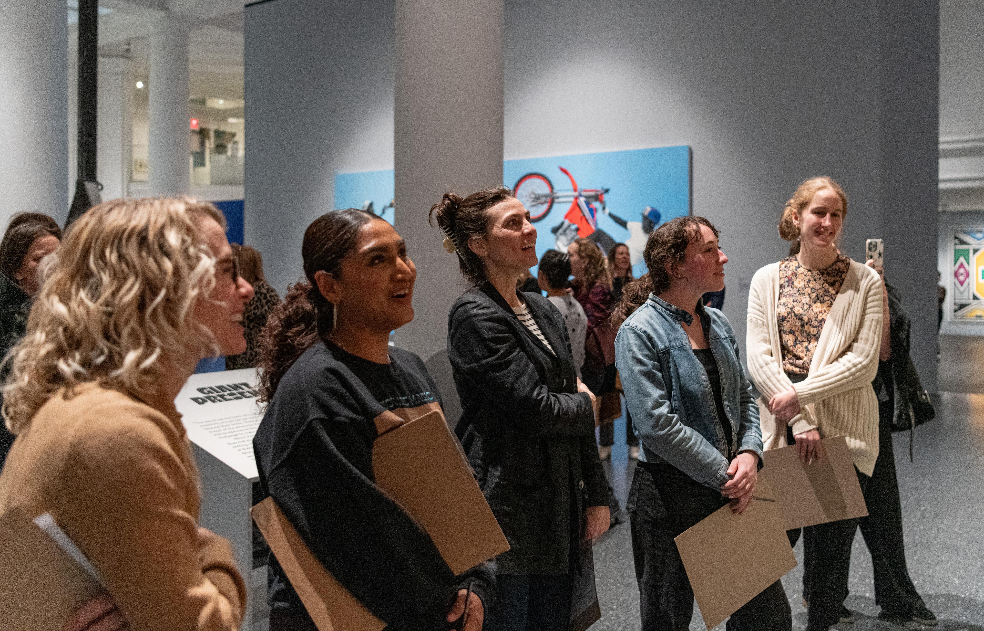 A group of five educators are smilling and talking to each other while looking at an artwork that is out of frame