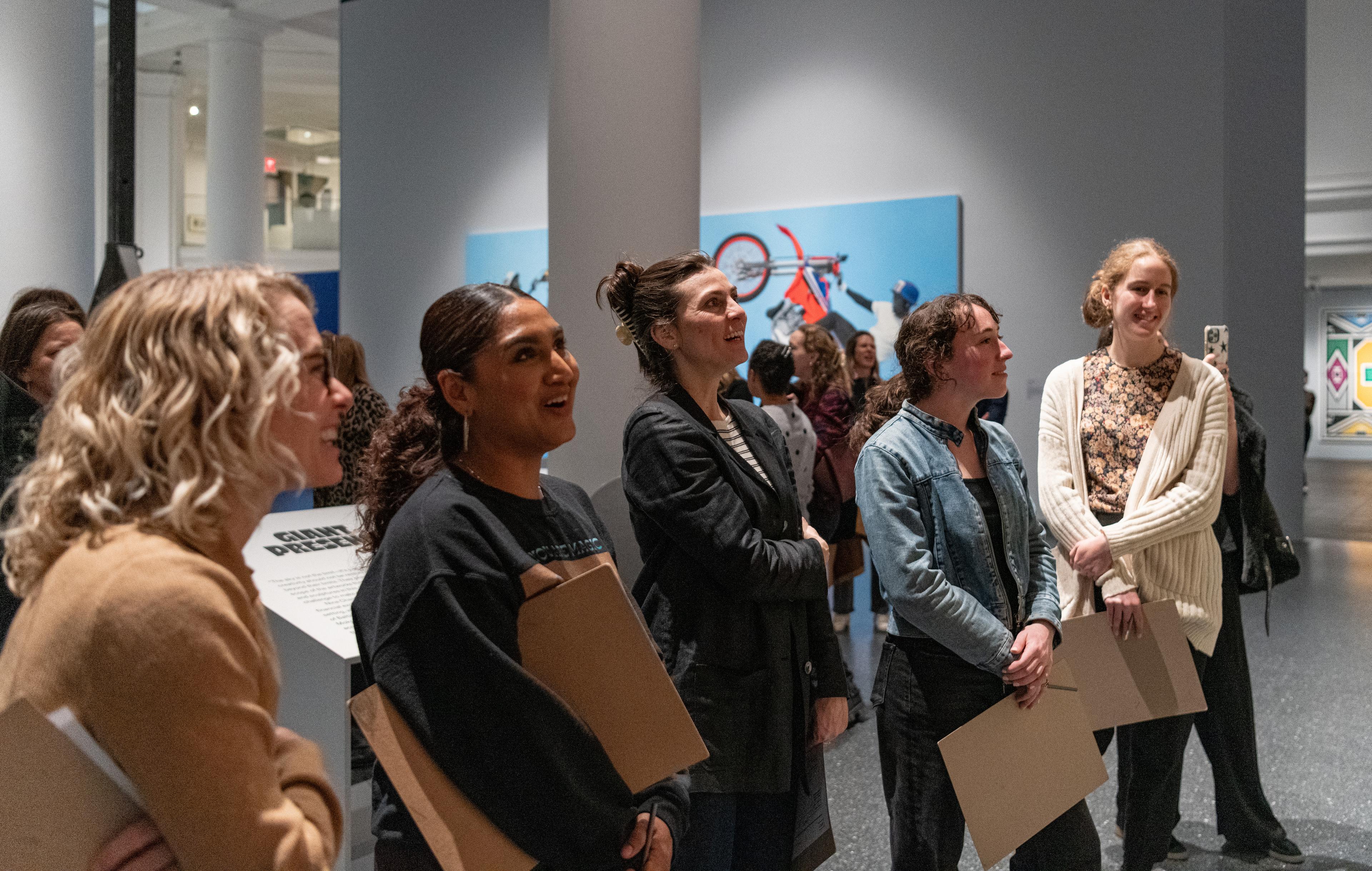 A group of five educators are smilling and talking to each other while looking at an artwork that is out of frame