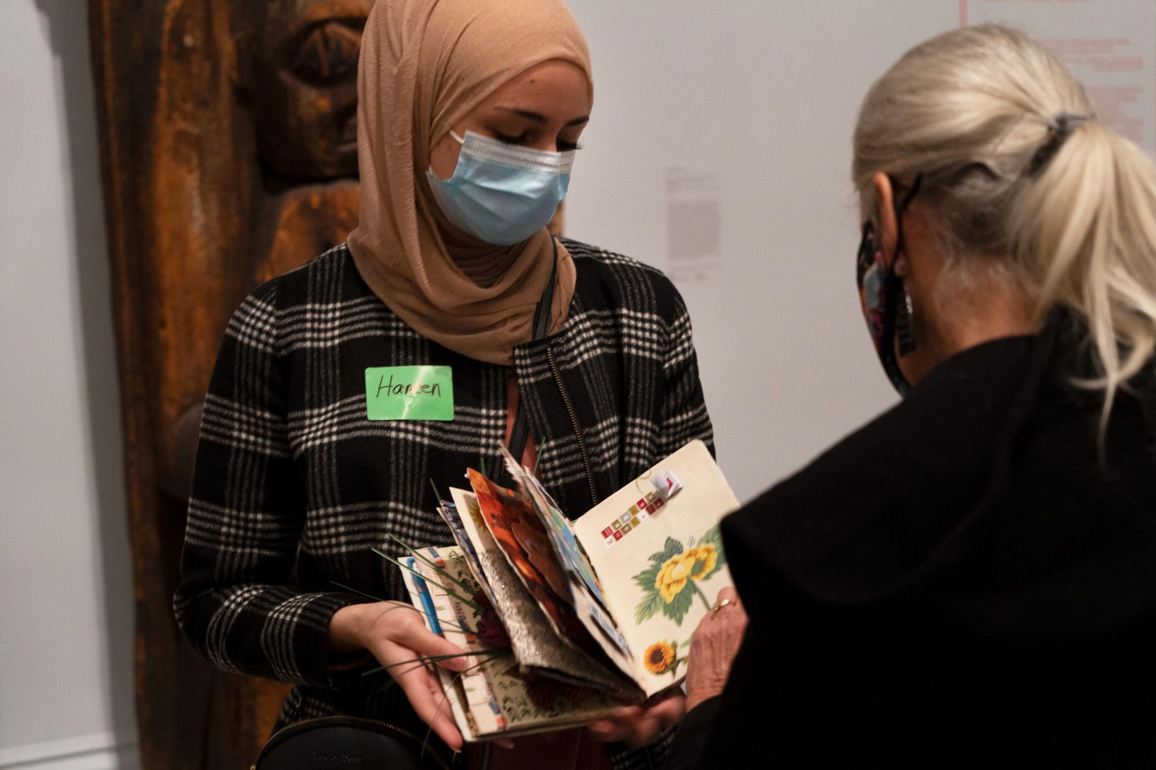 An ESOL student shares artwork created in a class partnership with a visitor in the Brooklyn Museum galleries. (Photo: Faviola Lopez-Romani)
