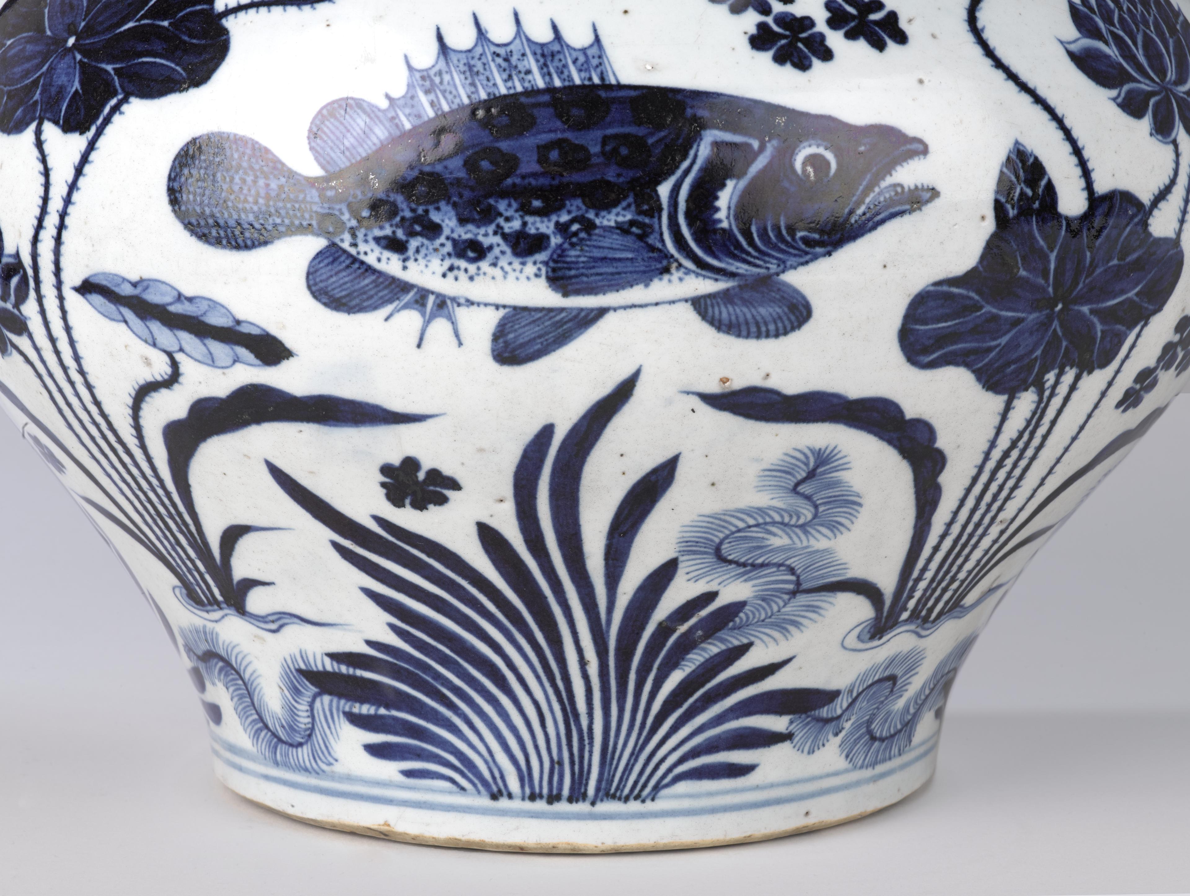 Close up detail of a white ceramic jar with a blue fish set in an aquatic scene