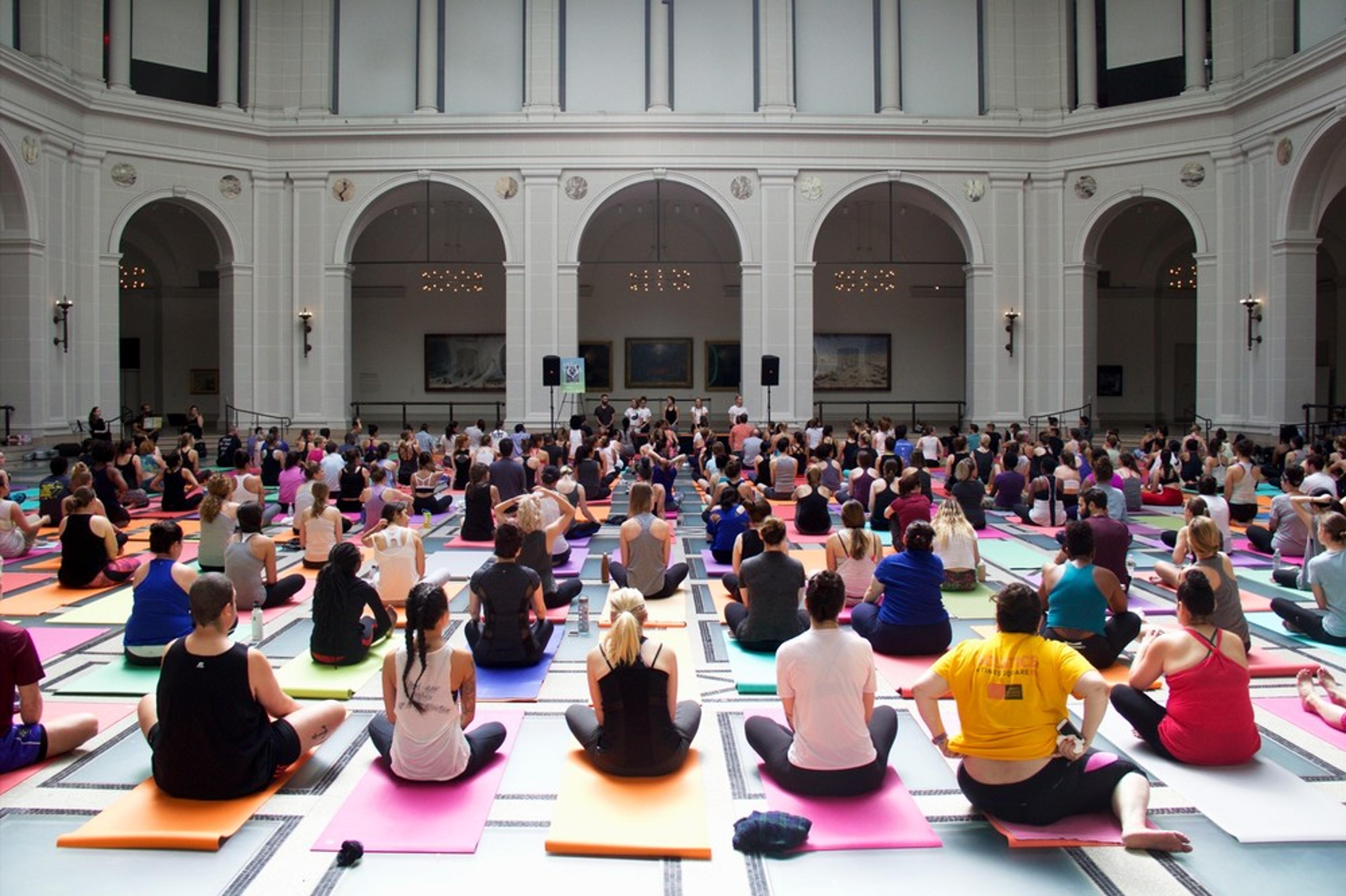 People seated on yoga mats in a large court