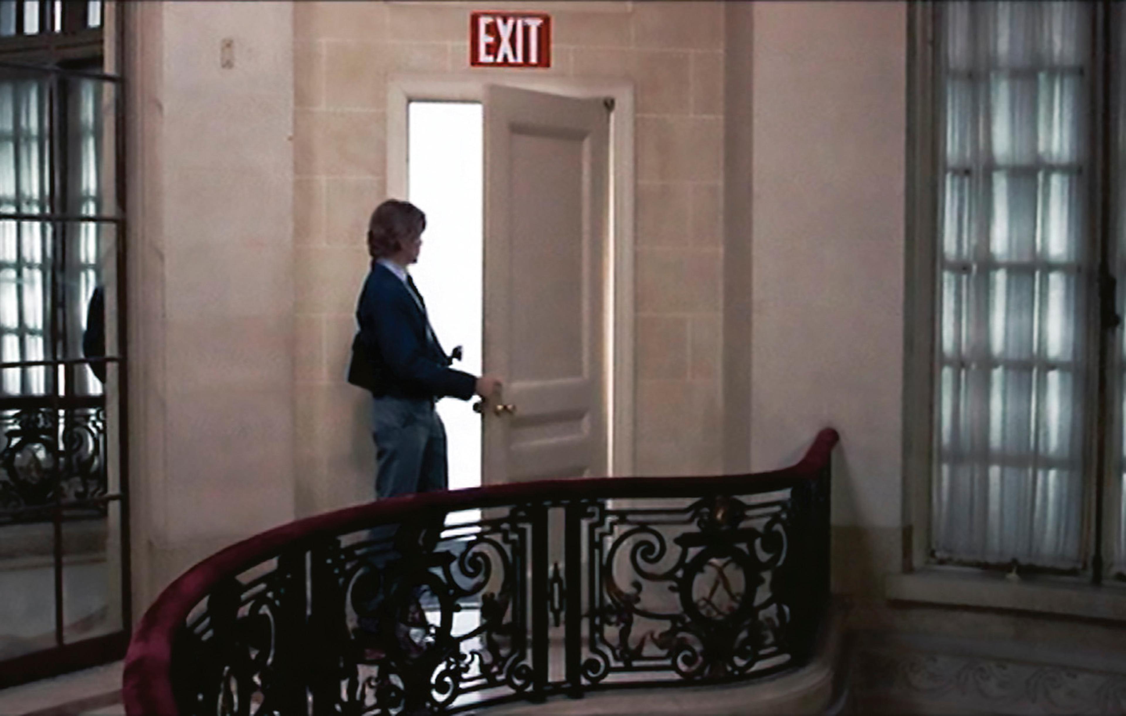 Film still showing a person looking out through a doorway