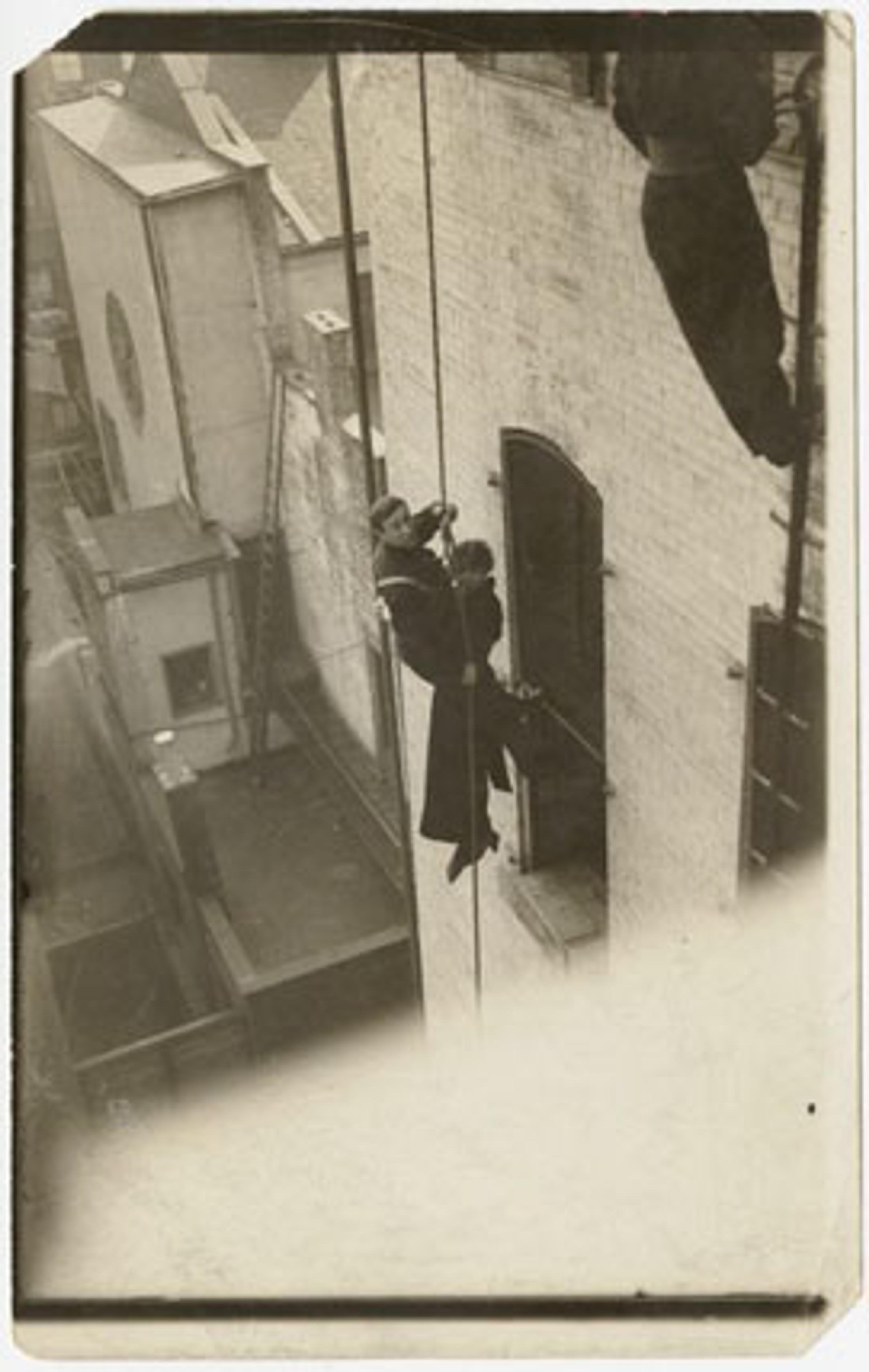 Djuna Barnes and unidentified fireman, dangling from a rope beside a building, October 1914. Gelatin silver photograph. Djuna Barnes Papers, Special Collections, University of Maryland Libraries