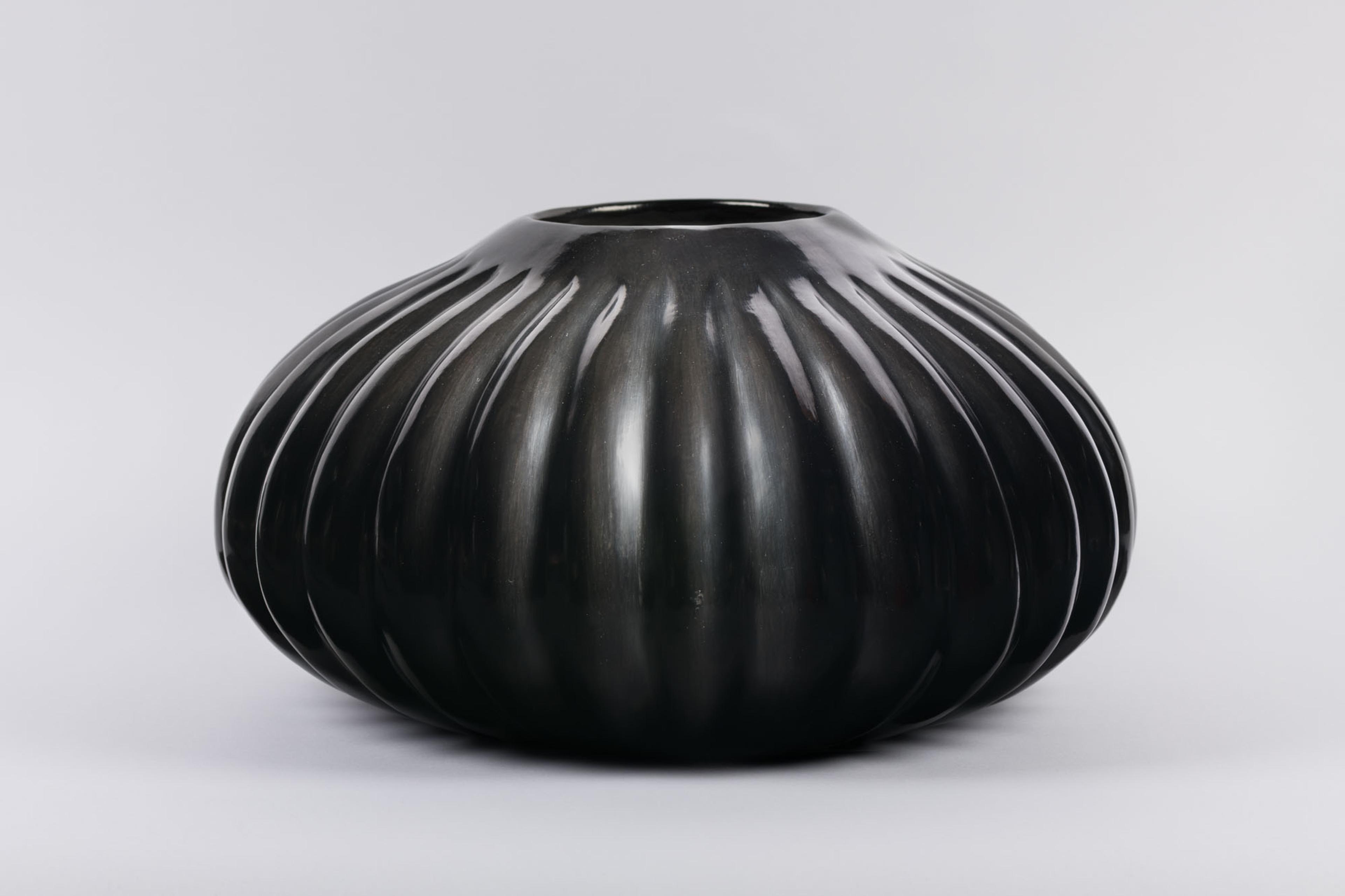 Photo of a black vase with vertical lines radiating acrossed it