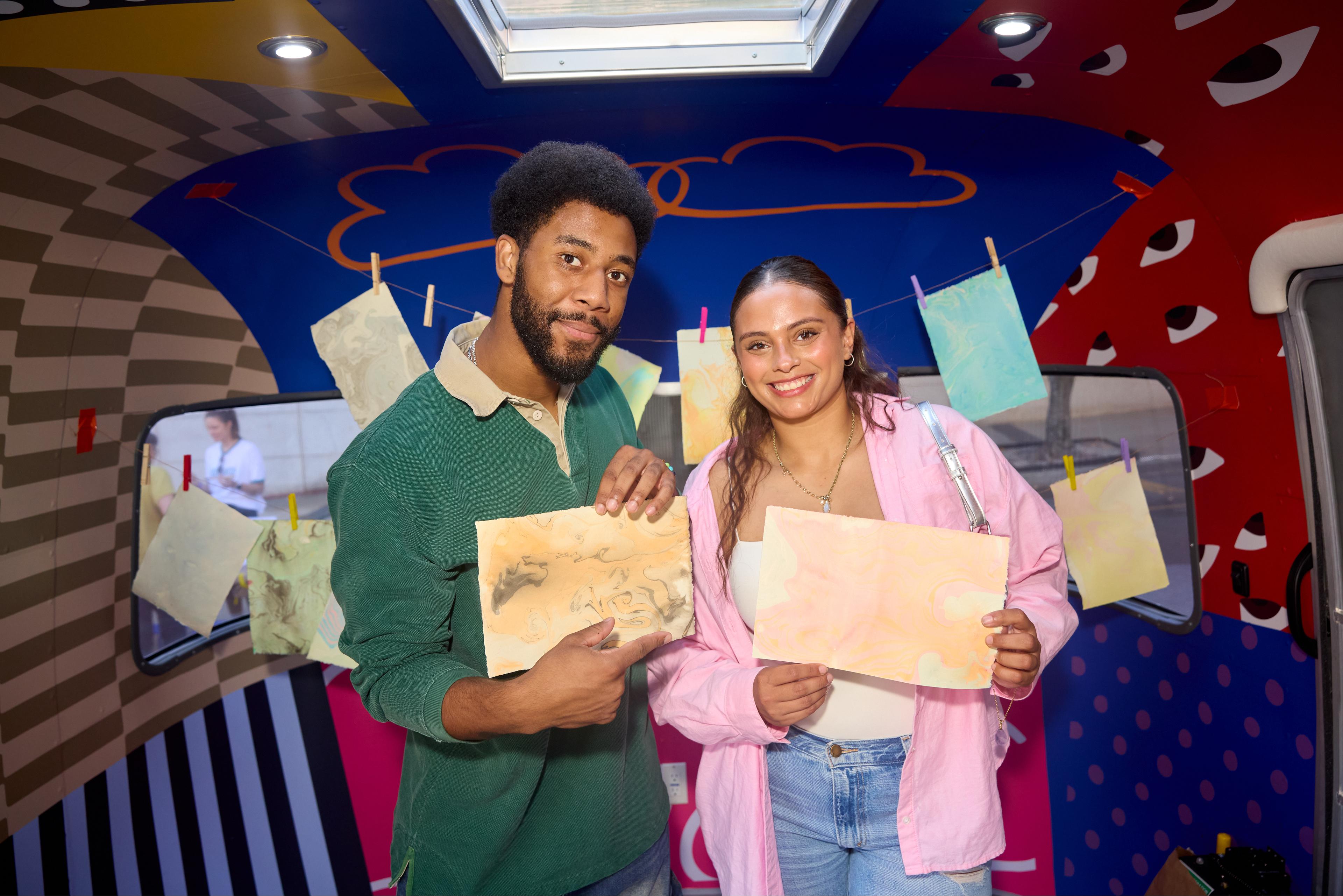 Two people holding works on paper