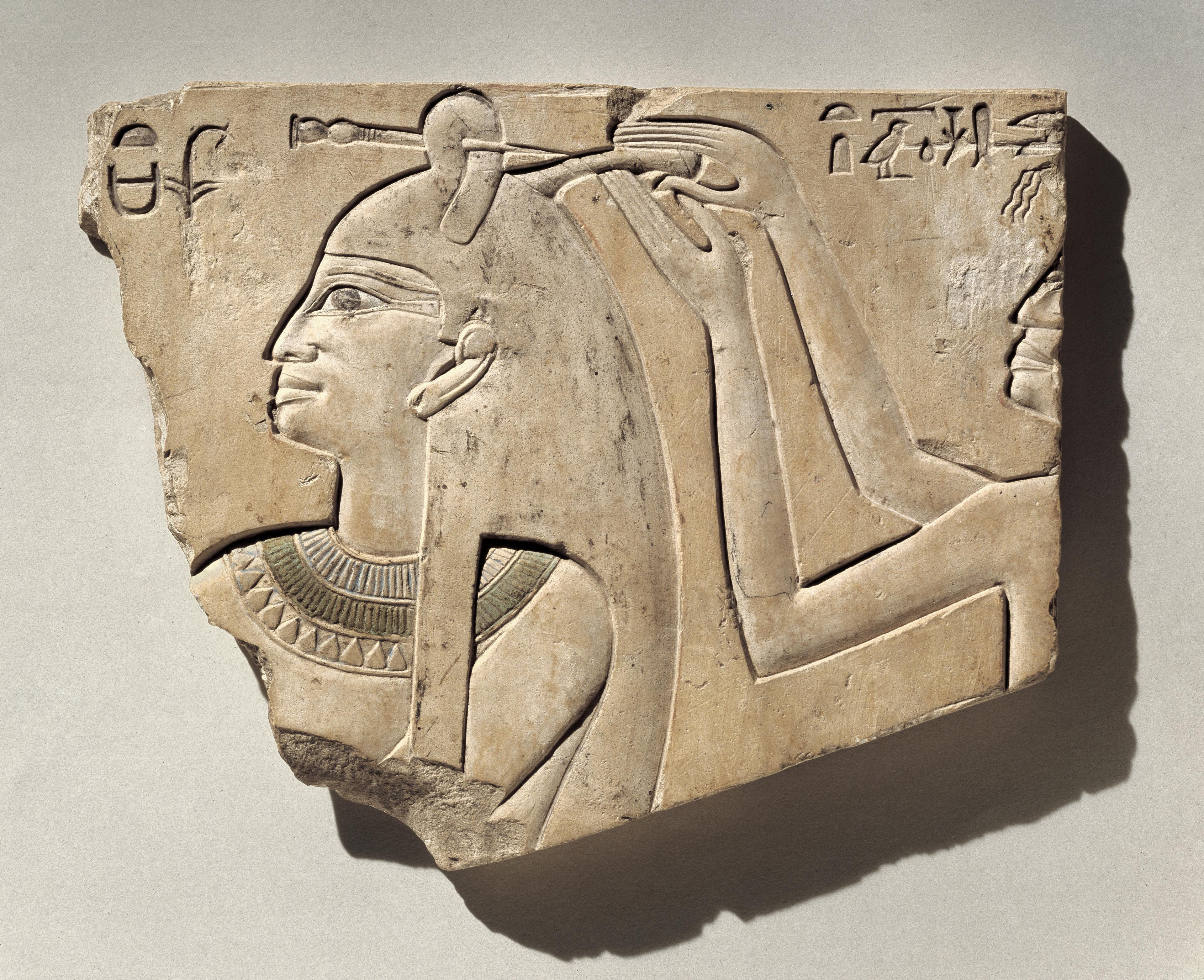 Ancient Egyptian relief of a figure with a headdress and hieroglyphs