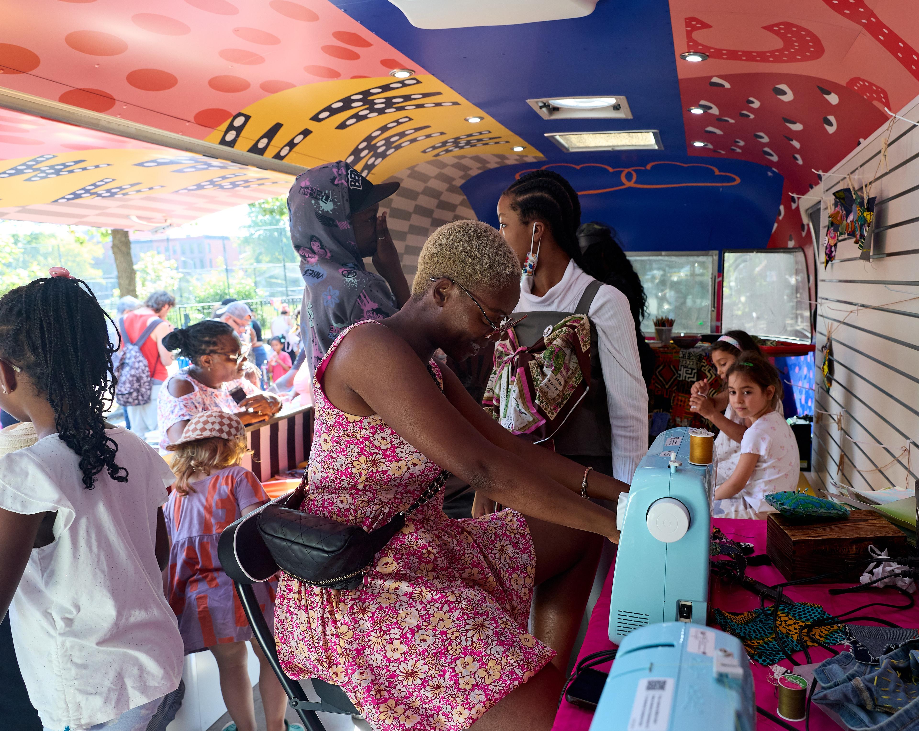 A person working at a sewing machine inside a colorful trailer