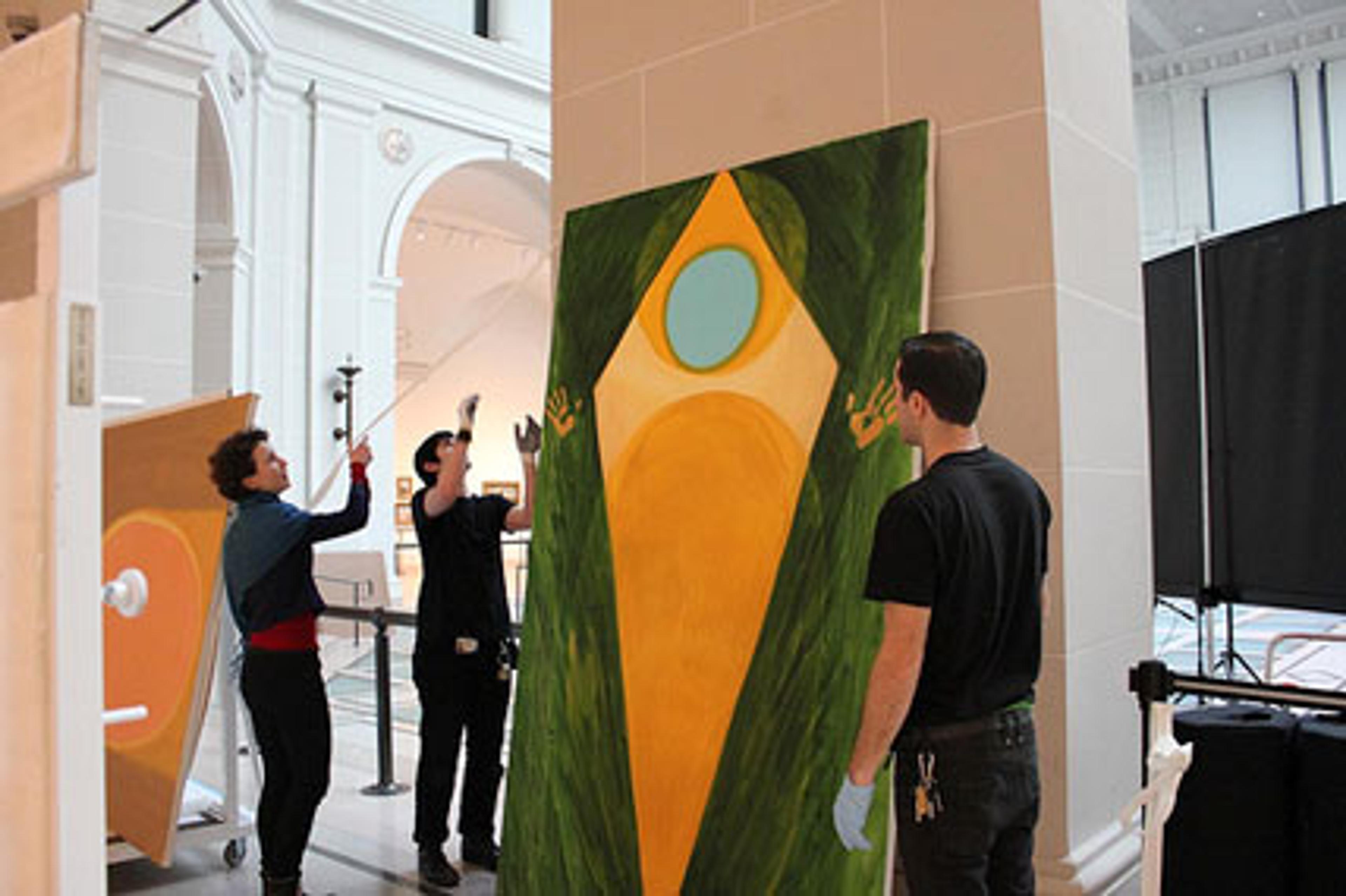 Shura Chernozatonskaya and Museum staff install Devotion, one of a pair of paintings that responds to the “Art and Devotion” section of the installation European Paintings, in the Beaux-Arts Court