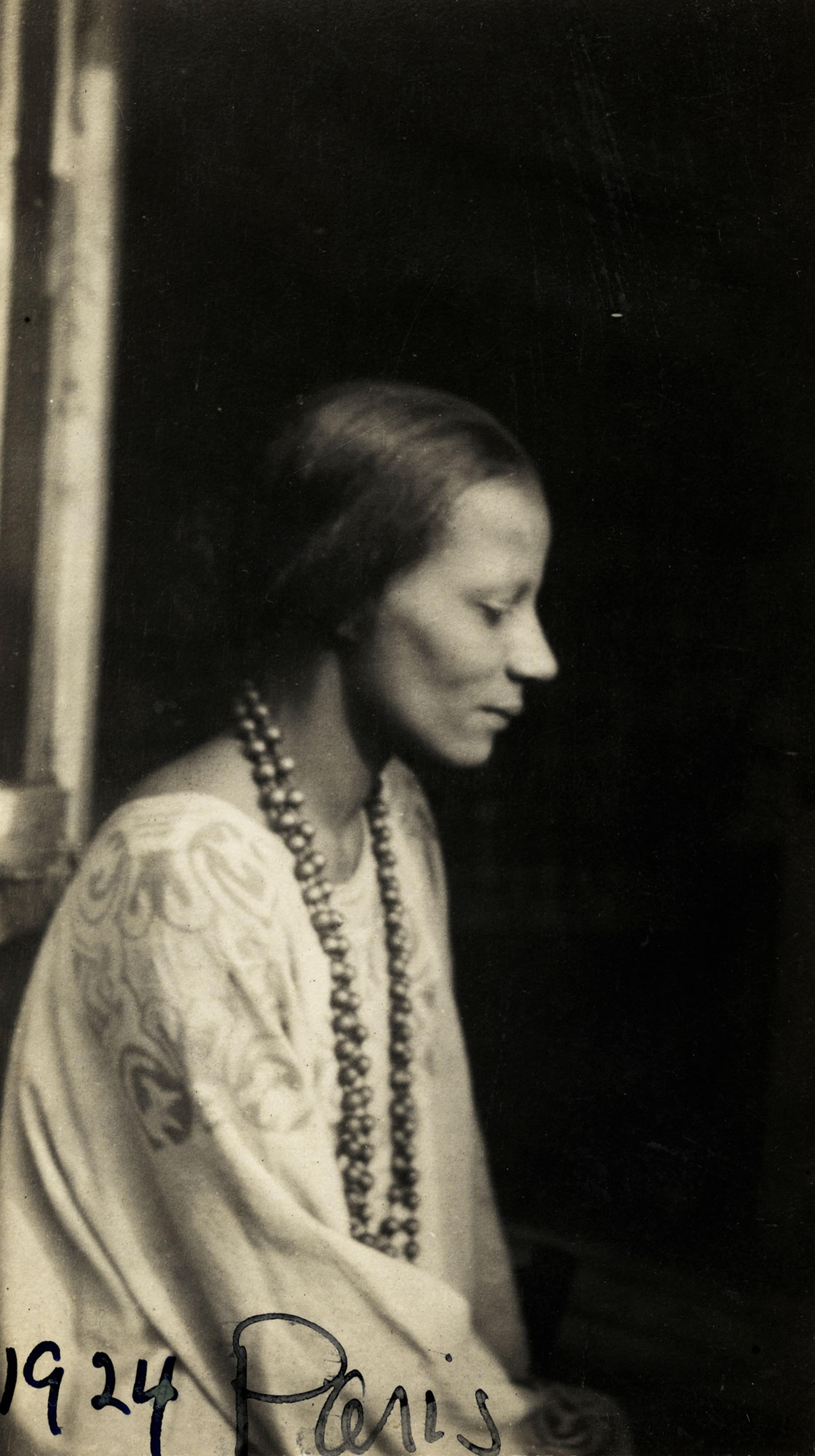 Black-and-white photograph of a woman wearing a long necklace