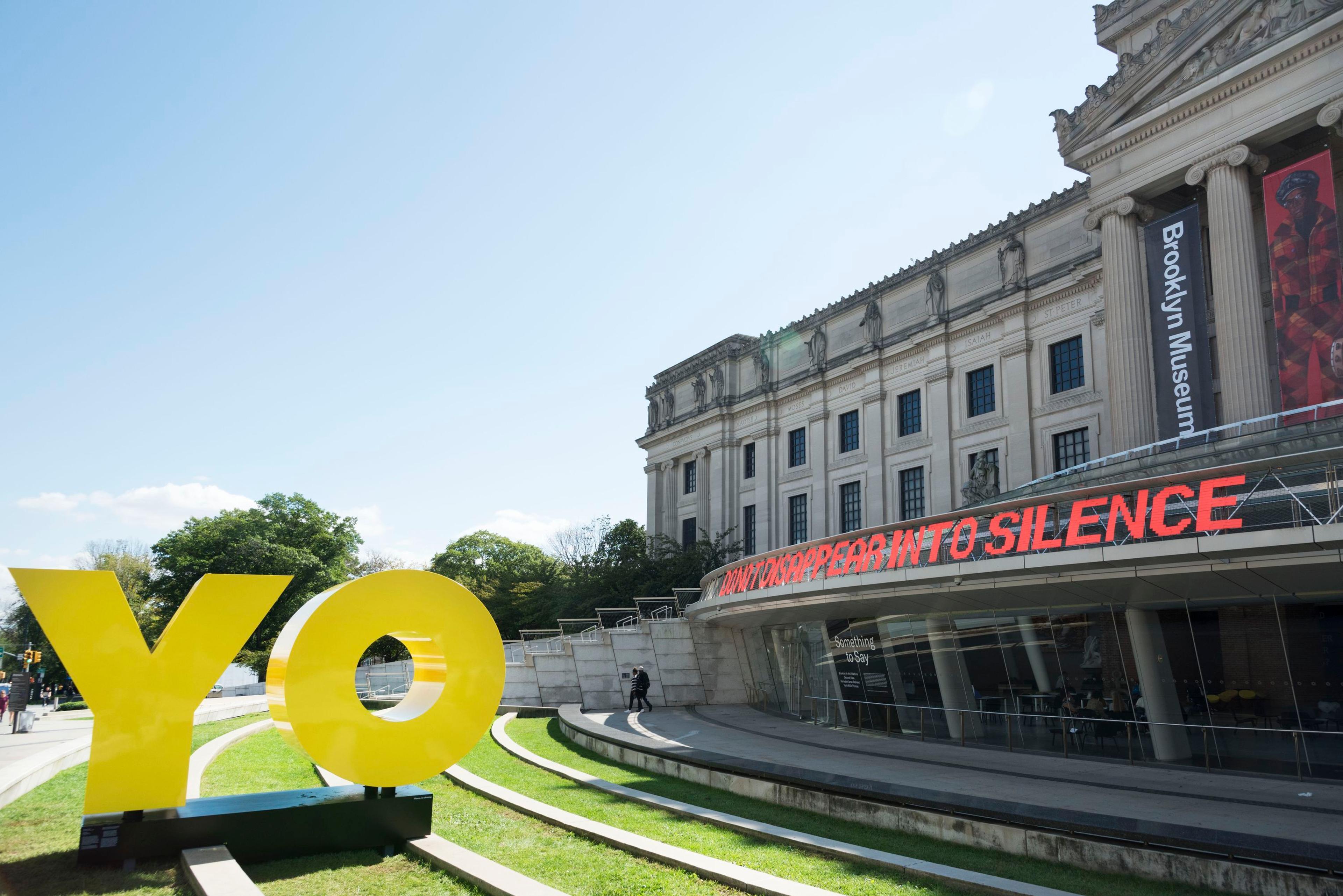 Exterior installation view, Something to Say: Brooklyn Hi-Art! Machine, Deborah Kass, Kameelah Janan Rasheed, and Hank Willis Thomas (visible: OY/YO, Deborah Kass; DO NOT DISAPPEAR INTO SILENCE, Brooklyn Hi-Art! Machine). Brooklyn Museum, October 3, 2018–June 30, 2019. © 2018 Deborah Kass/Artists Rights Society (ARS), New York. (Photo: Jonathan Dorado)