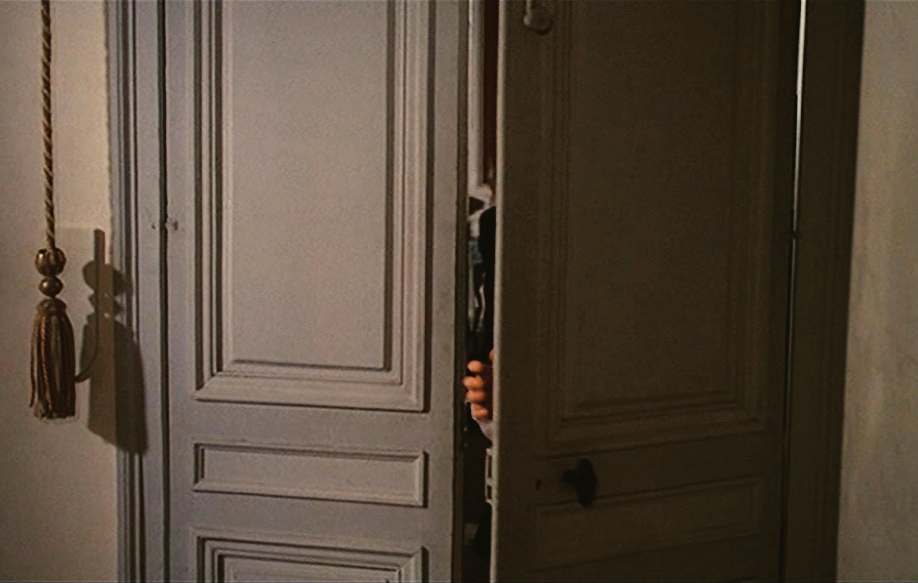 Film still showing a hand opening a door