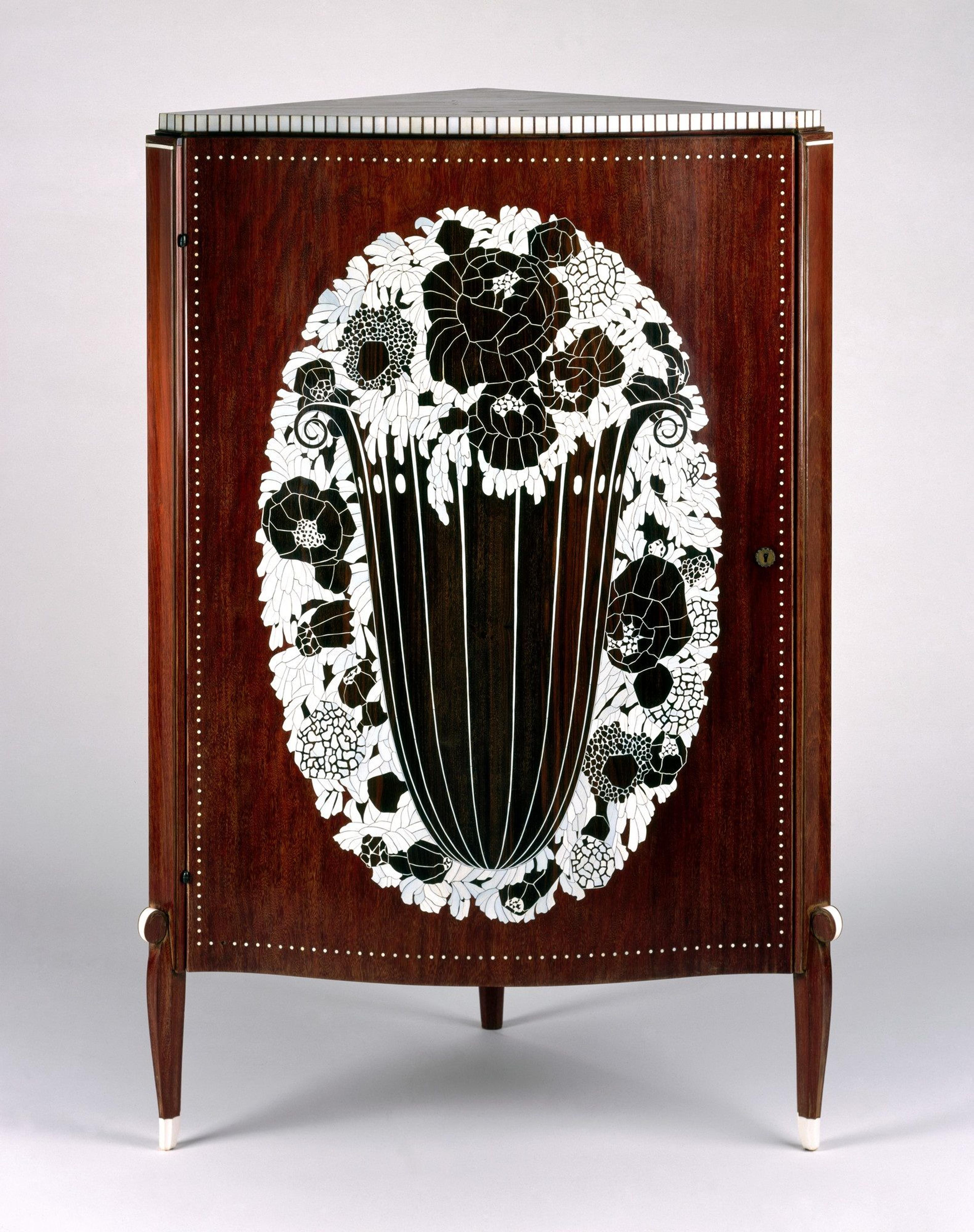 A wooden cabinet with floral inlay design, featuring a central vase motif surrounded by intricate white and black flowers