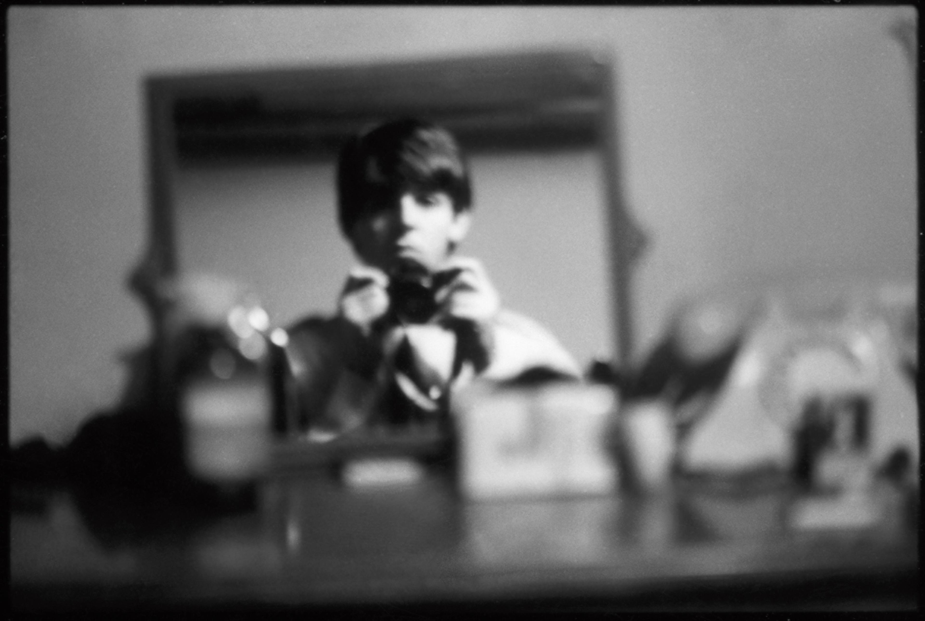 A black-and-white image of young Paul McCartney taking his own photo in a mirror