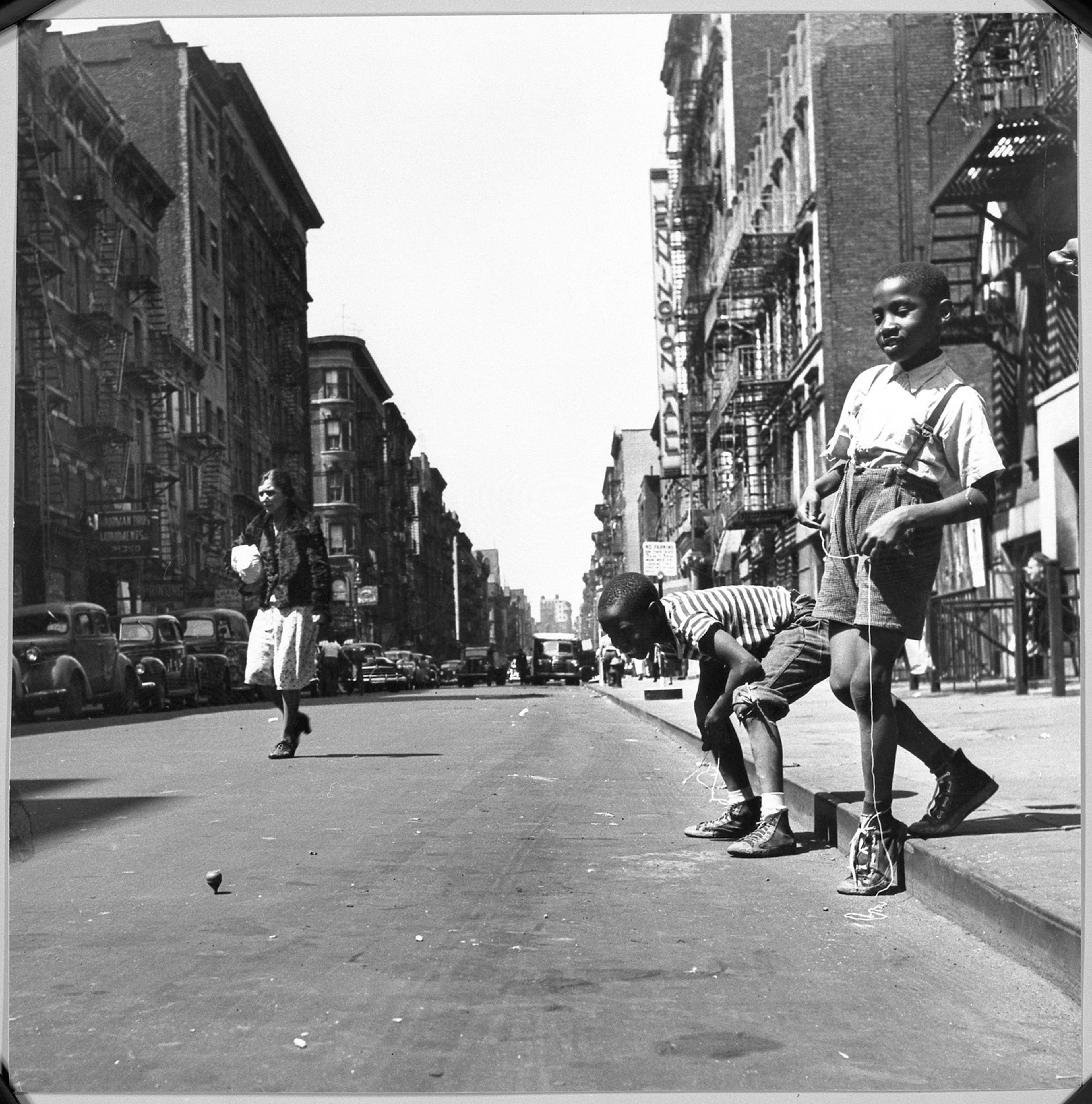 Print showing children playing with tops on a city street