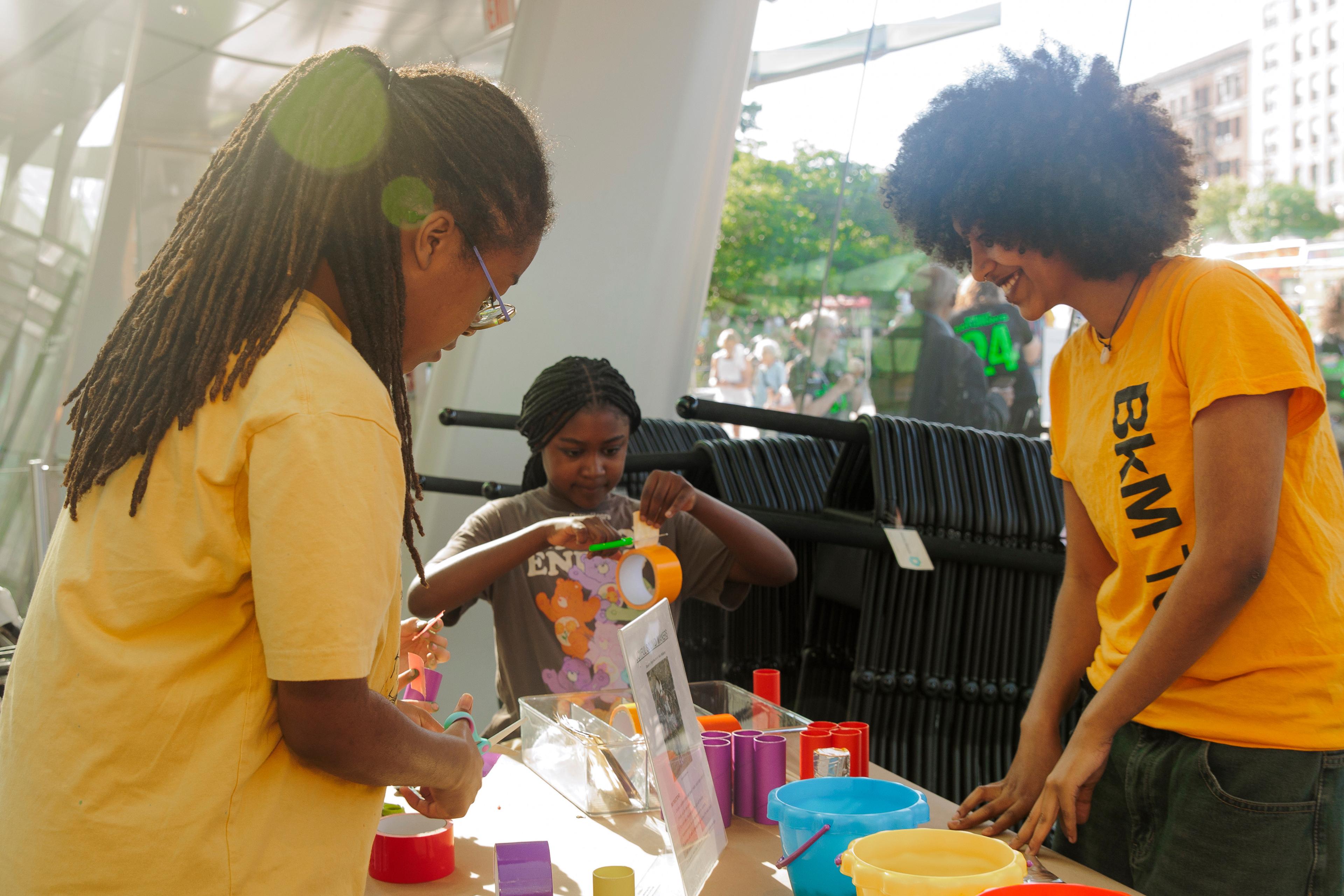 Three people lean over a craft project at a table