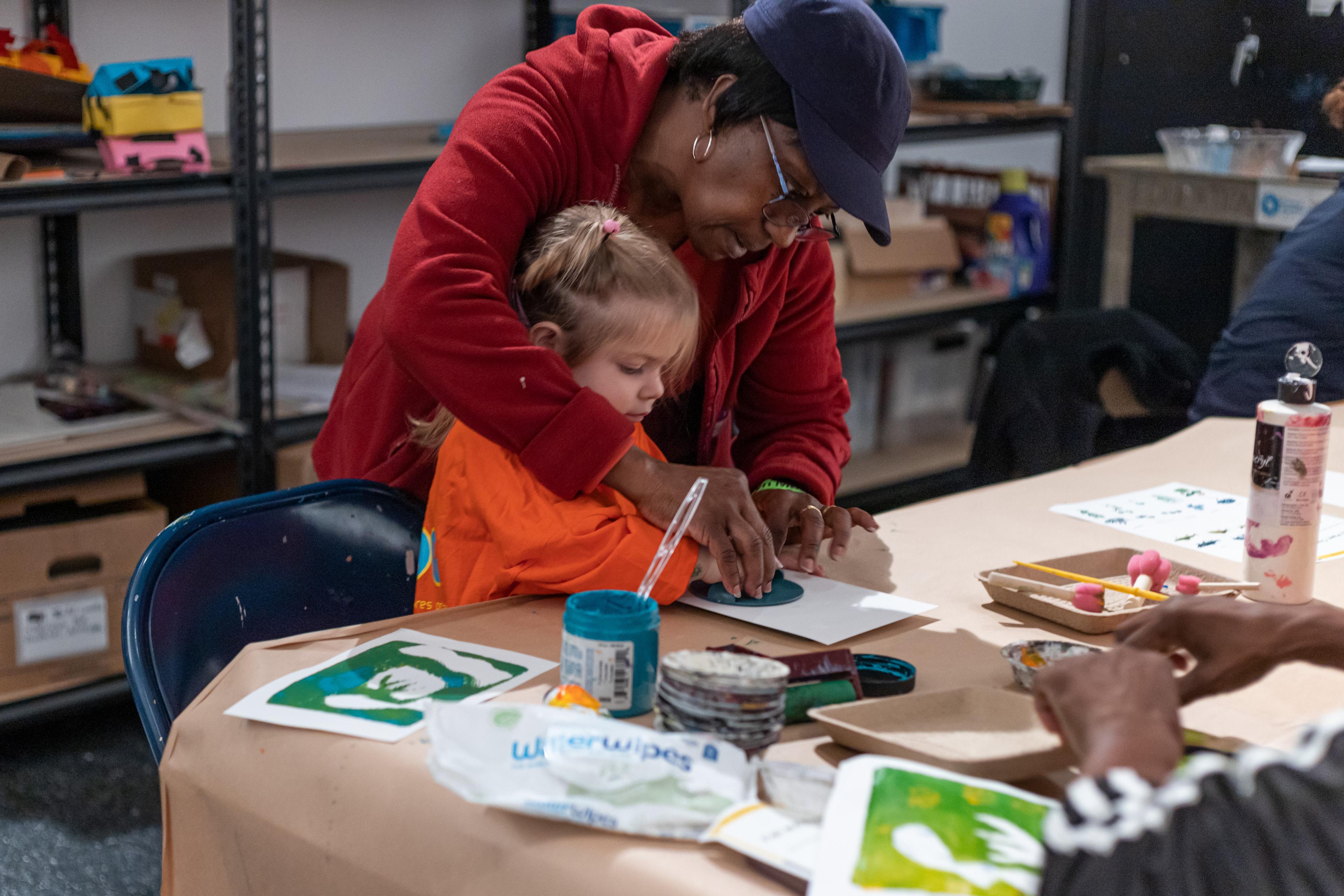 An adult helping a child create an artwork