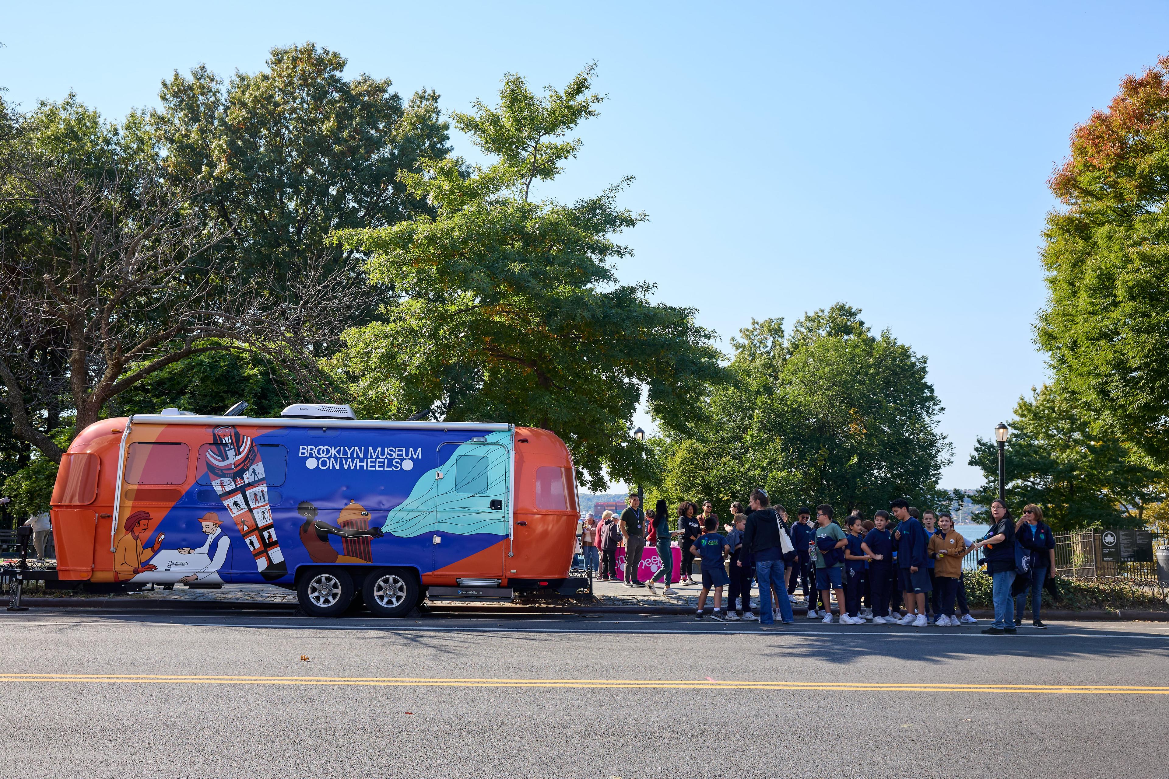 Museum on Wheels trailer parked on a curbside near a crowd