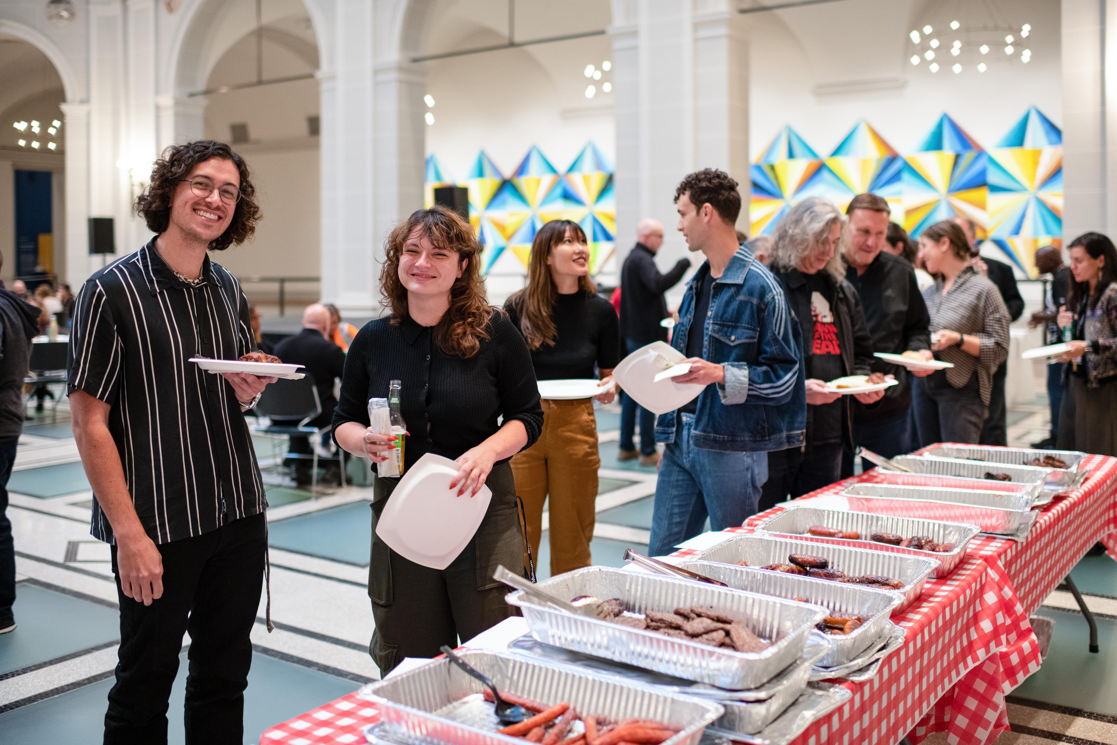 Staff members smile and chat near a buffet table