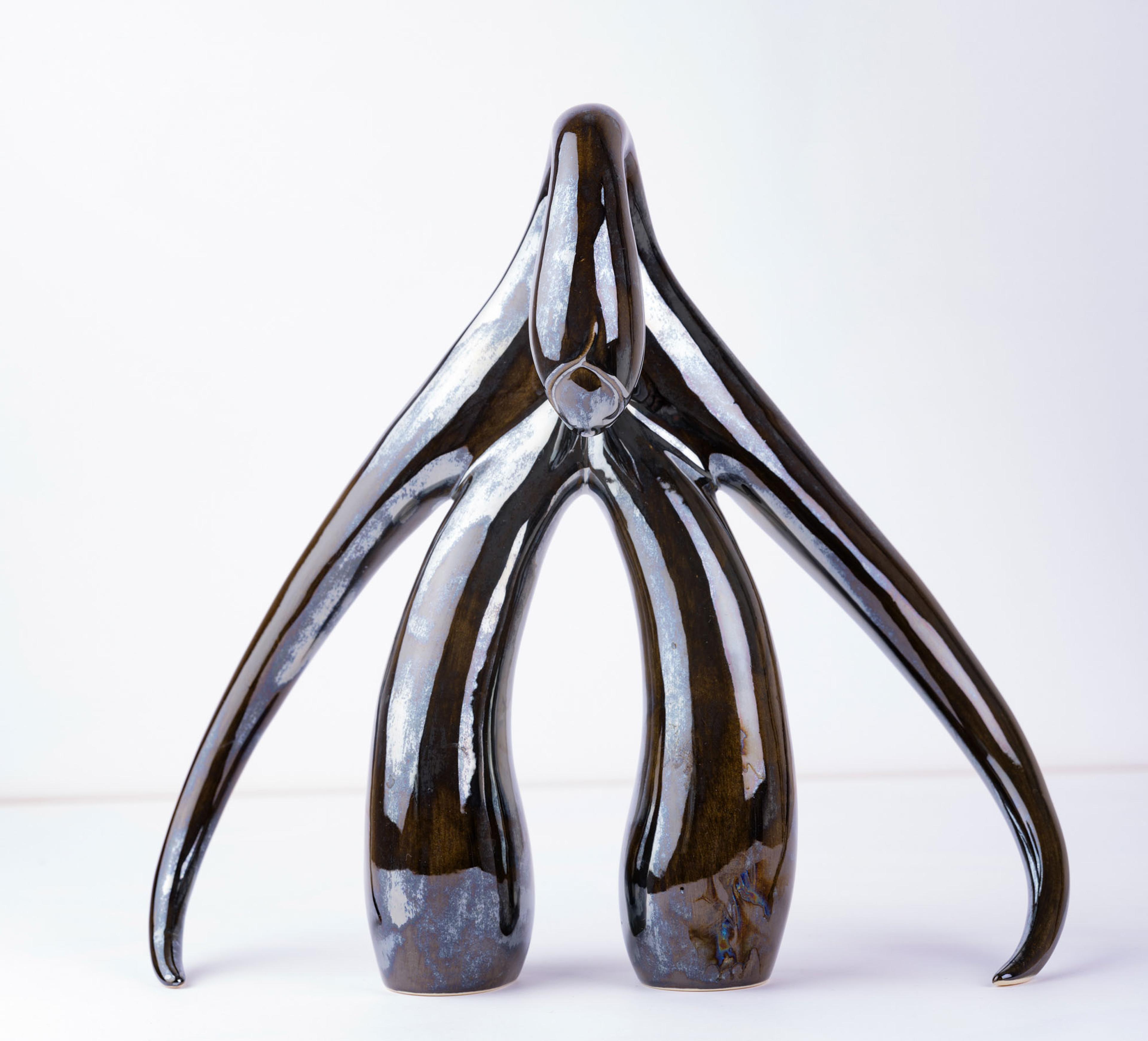 A glossy ceramic sculpture with organic, flowing shapes