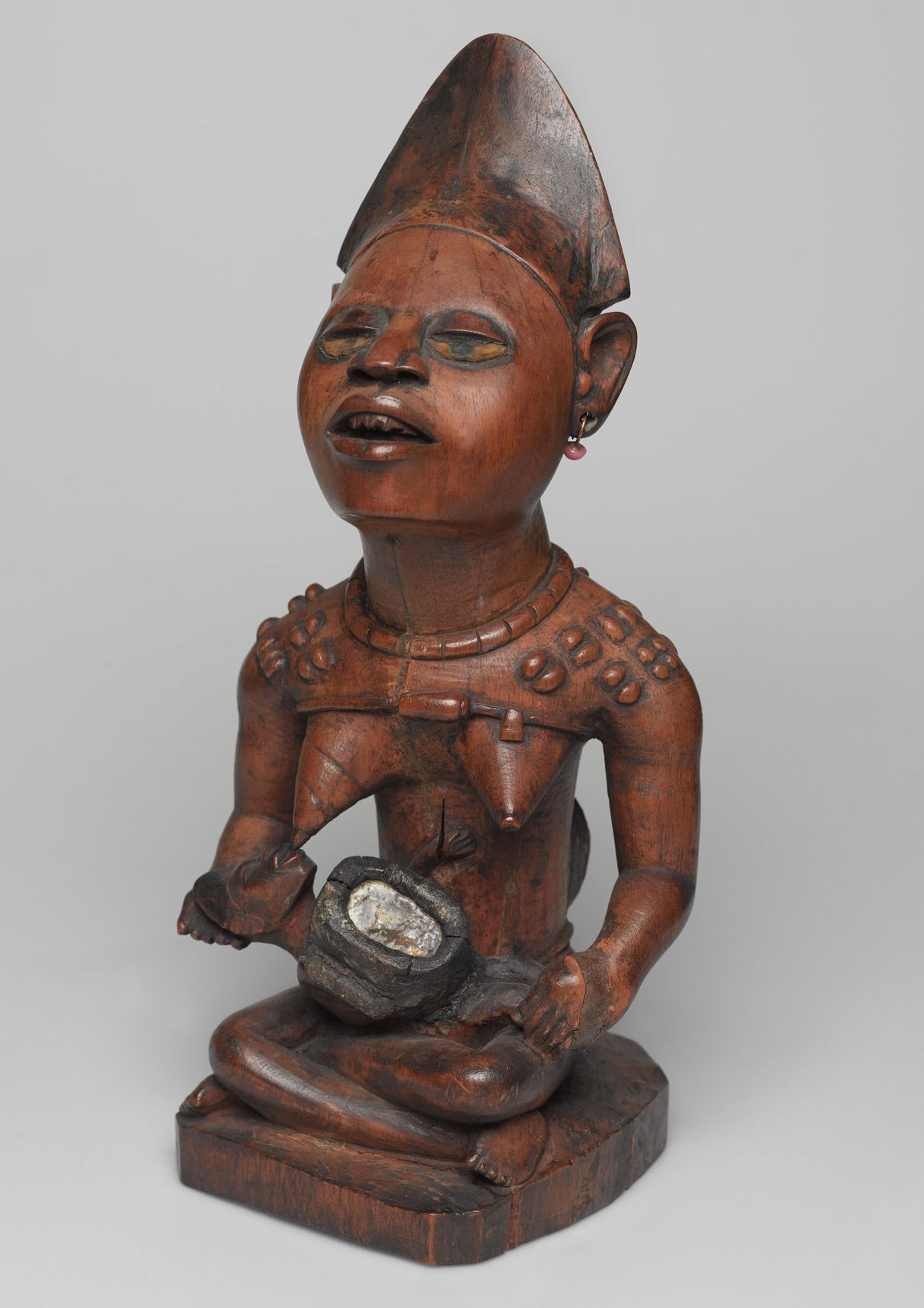 Kongo (Yombe subgroup) artist. Power Figure (nkisi): Woman and Child, 19th century. Wood, glass, upholstery studs, metal, metal and glass buttons, resin, 11 × 5 × 41/2 in. (27.9 × 12.7 × 11.4 cm). Brooklyn Museum; Museum Expedition 1922, Robert B. Woodward Memorial Fund, 22.1138. (Photo: Brooklyn Museum)