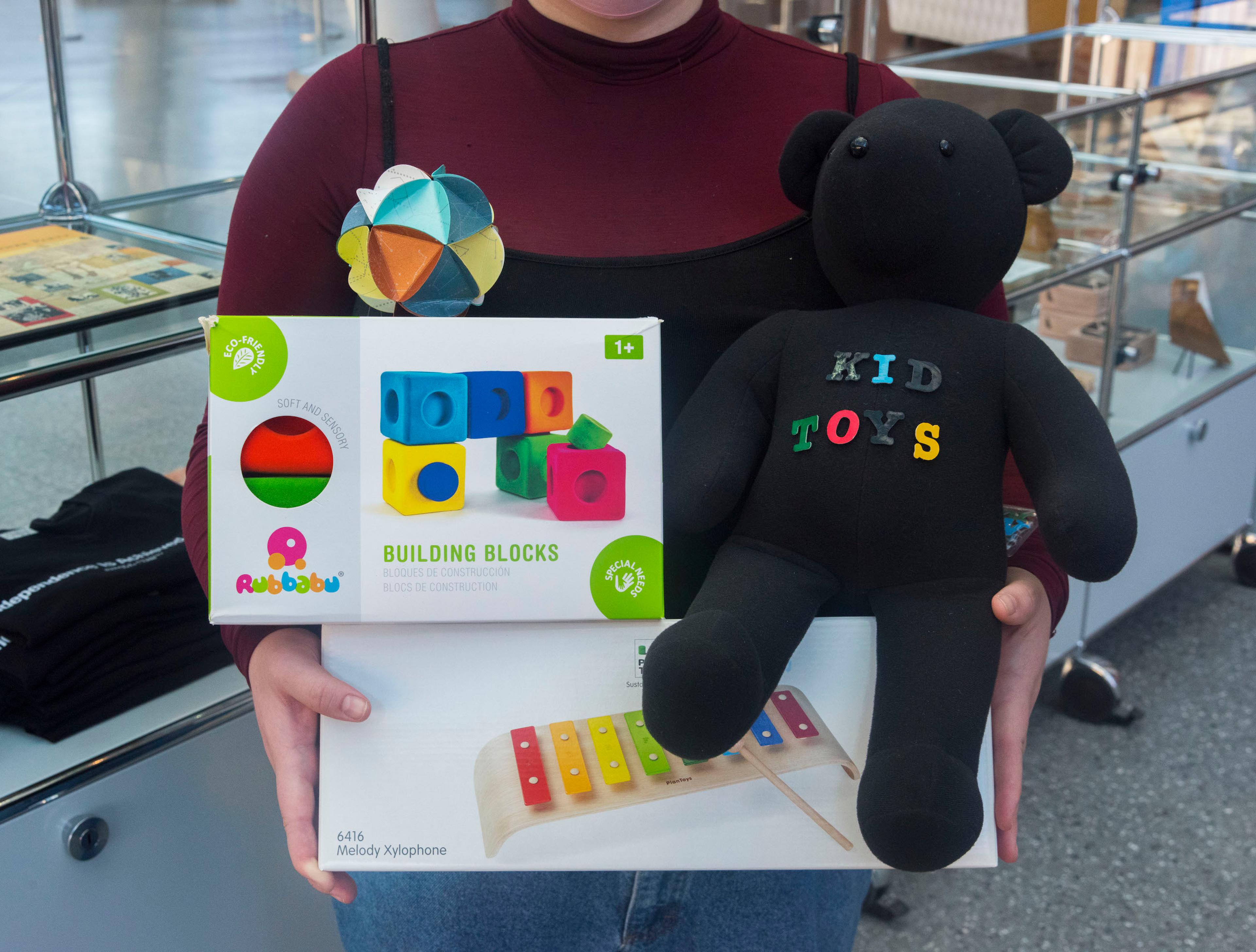 Person in a maroon turtle neck holds a variety of toys