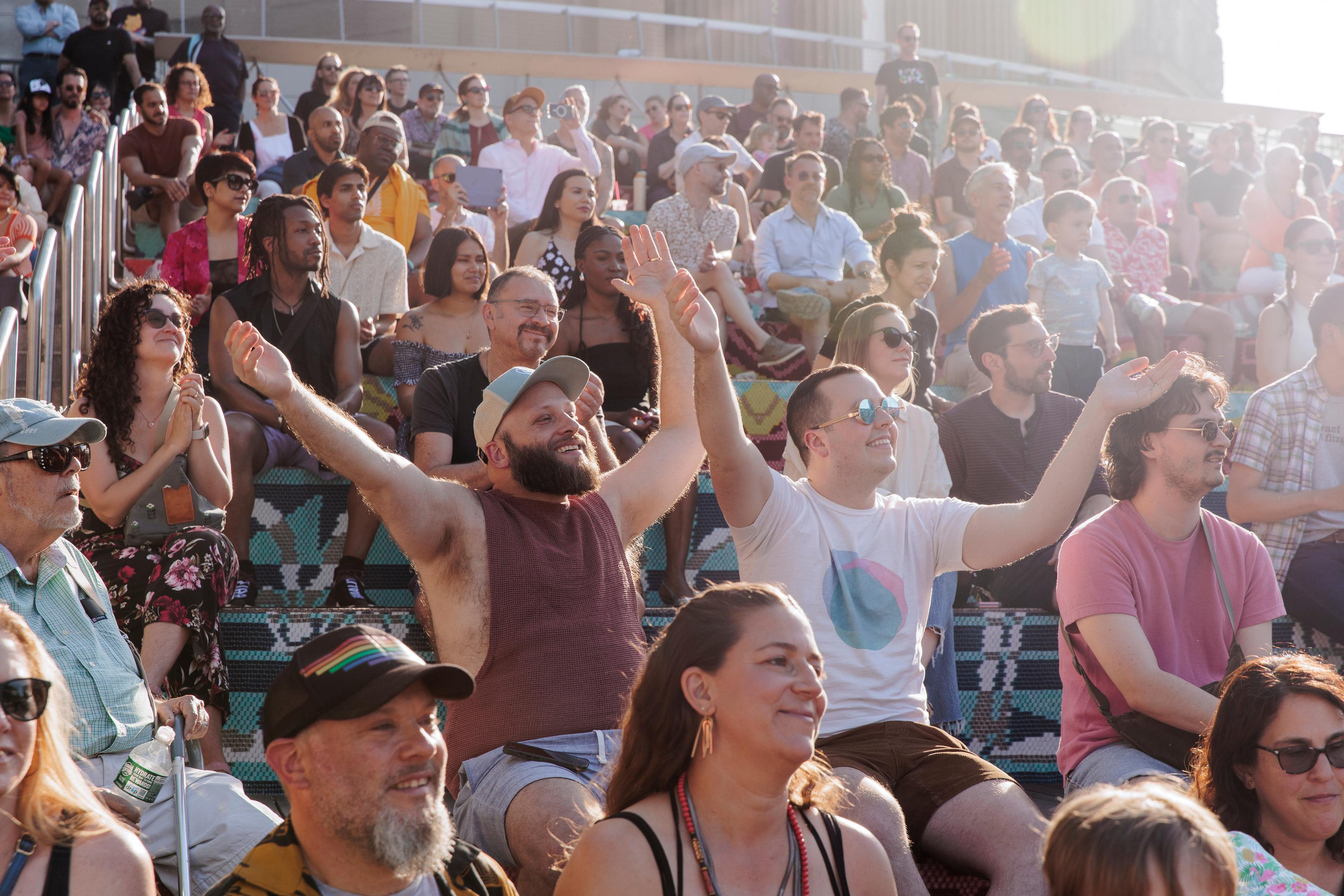 A joyful crowd sits on steps of the Brooklyn Museum plaza