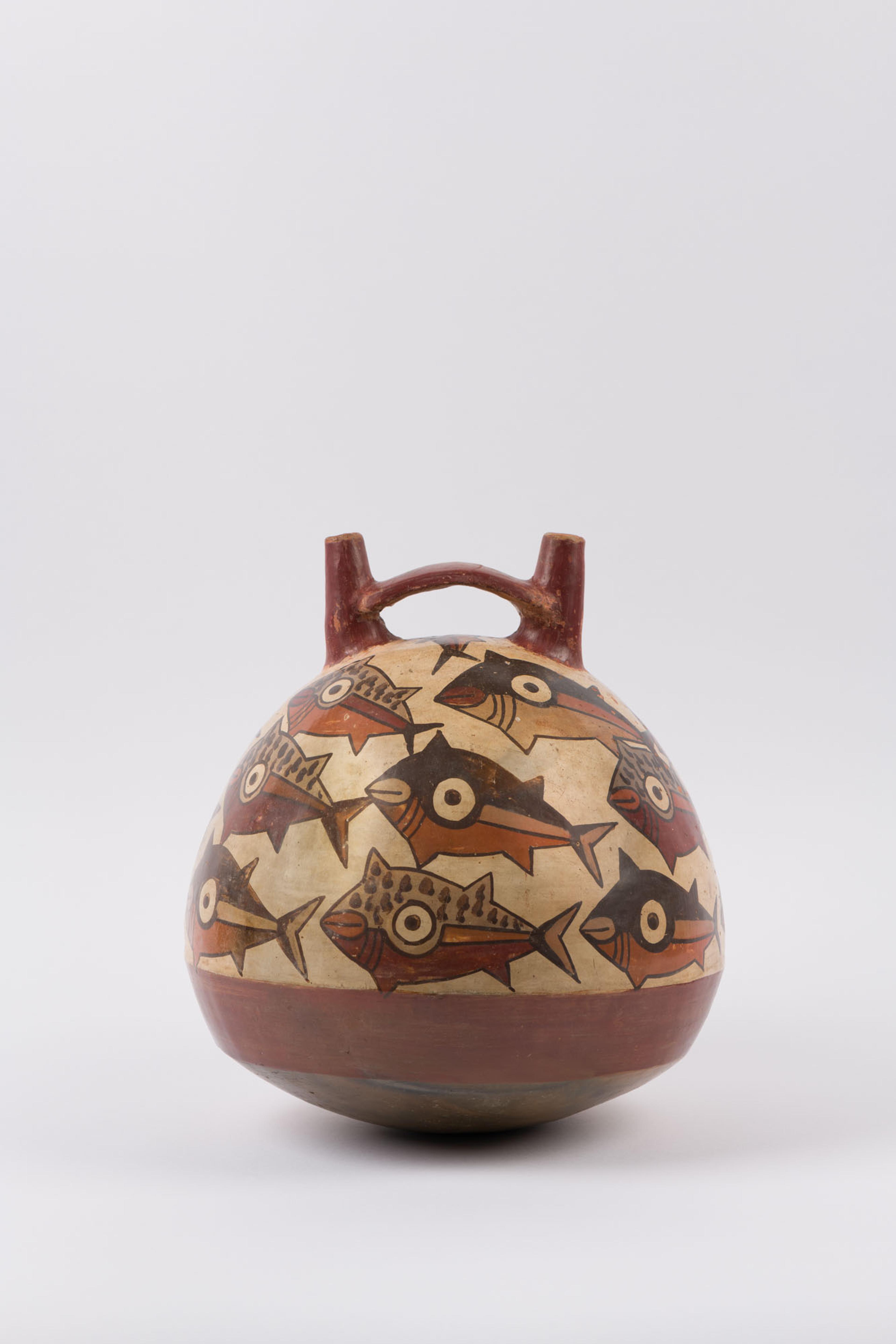 Photo of a tan vessel with two spouts, featuring a pattern of wide-eyed fish