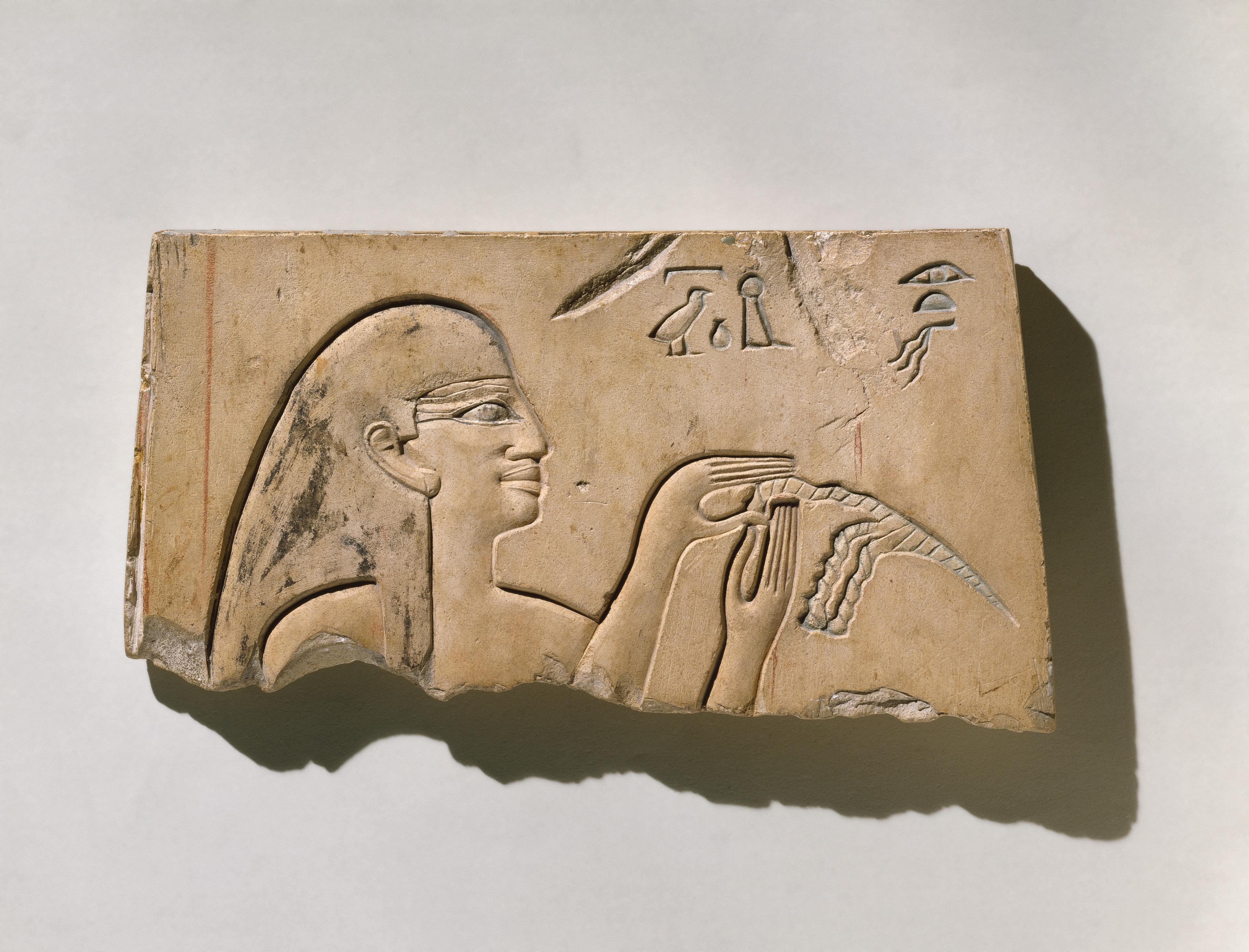 Ancient Egyptian relief of a figure with a headdress and hieroglyphs