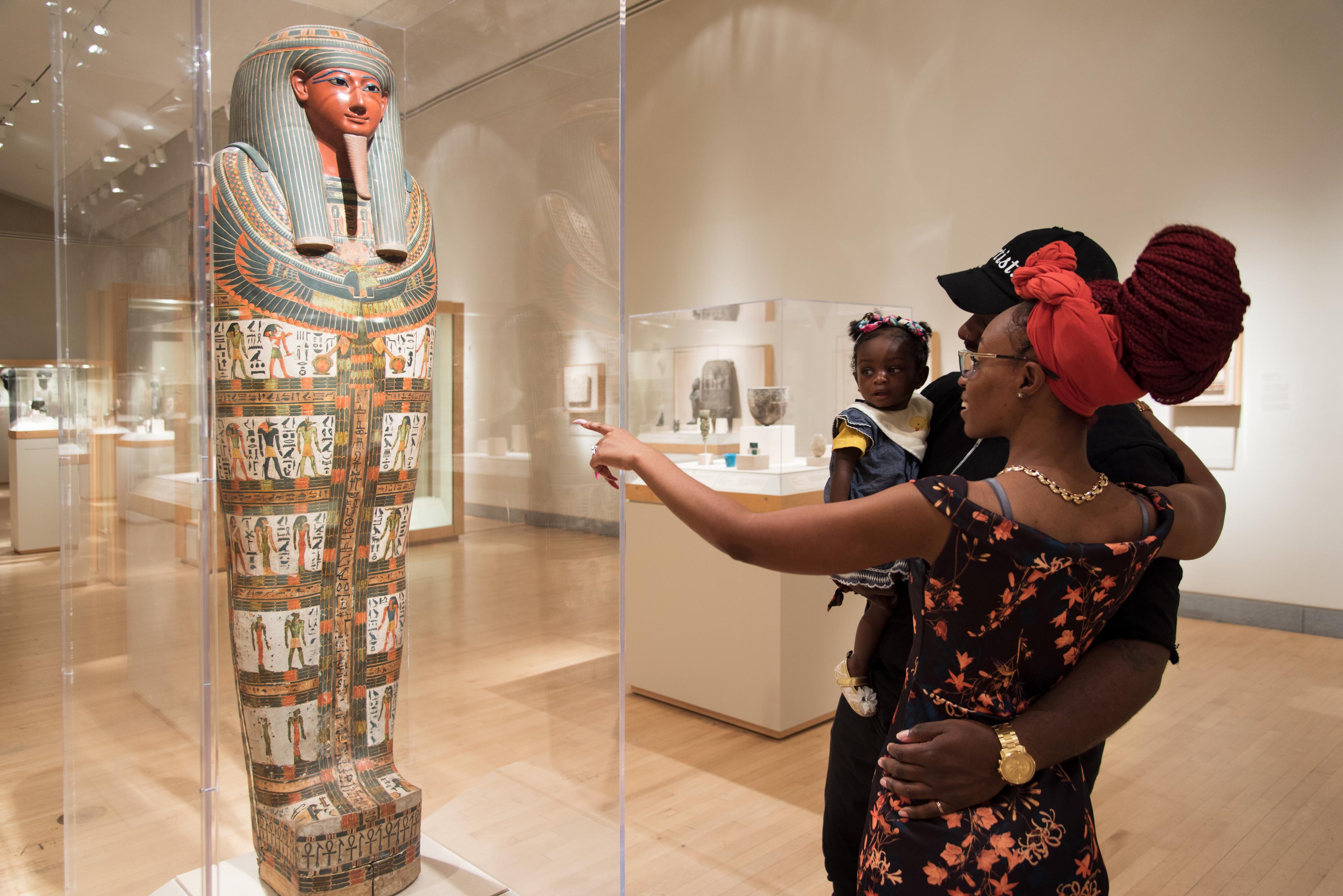 A family viewing an Egyptian sarcophagus in a gallery