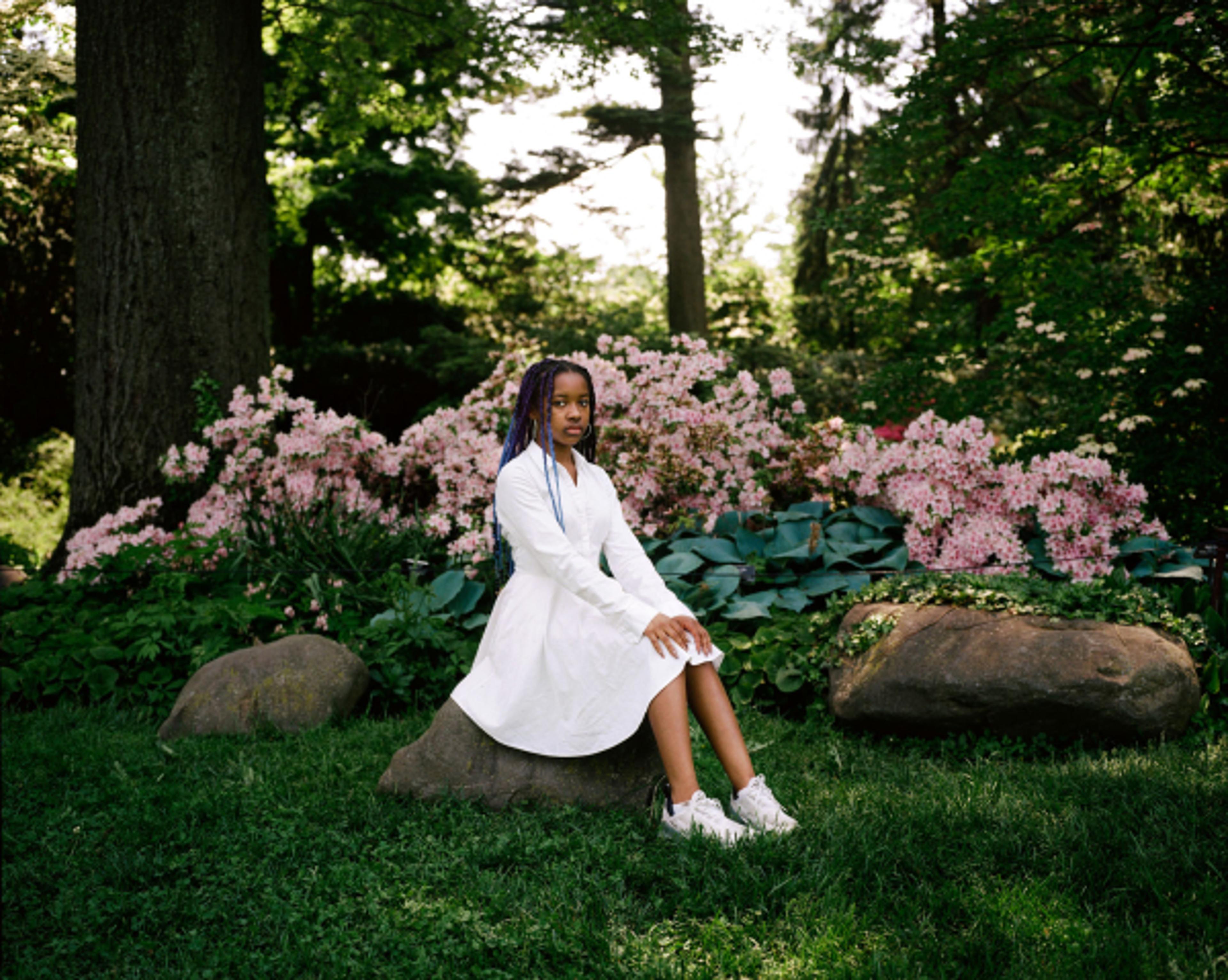 Photograph of a girl sitting on a rock in a park